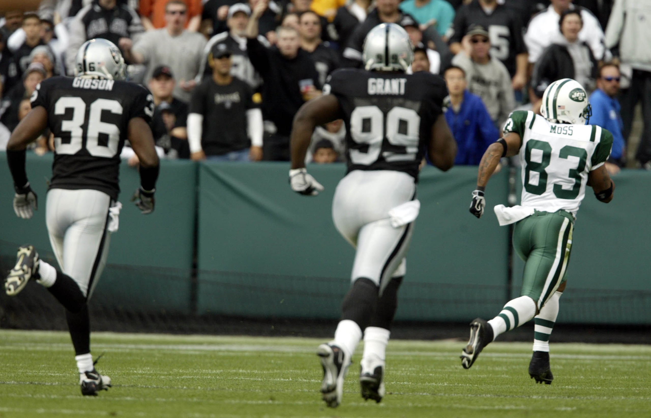 OAKLAND, CA - NOVEMBER 9:   Santana Moss #83  of the New York Jets runs after the catch for a touchdwon as Derrick Gibson #36 and DeLawrence Grant #99 of the Oakland Raiders give chase during an NFL game on November 9, 2003  at the Network Associates Coli