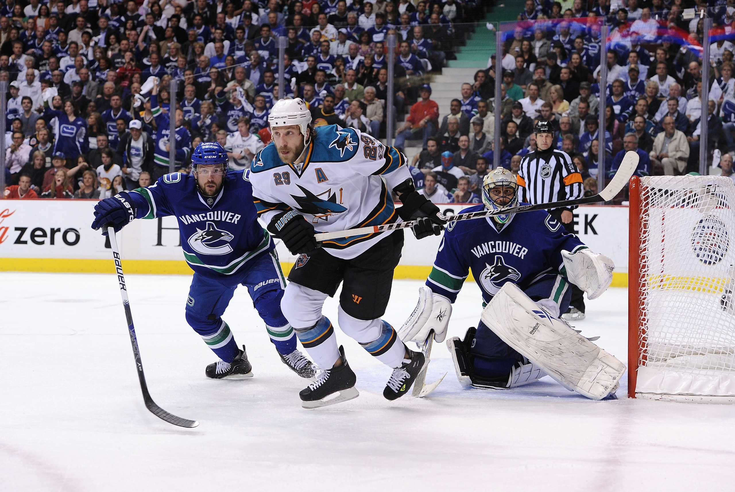 VANCOUVER, CANADA - MAY 24:  Ryane Clowe #29 of the San Jose Sharks, goaltender Roberto Luongo #1 and Keith Ballard #4 of the Vancouver Canucks look to the corner in Game Five of the Western Conference Finals during the 2011 Stanley Cup Playoffs at Rogers
