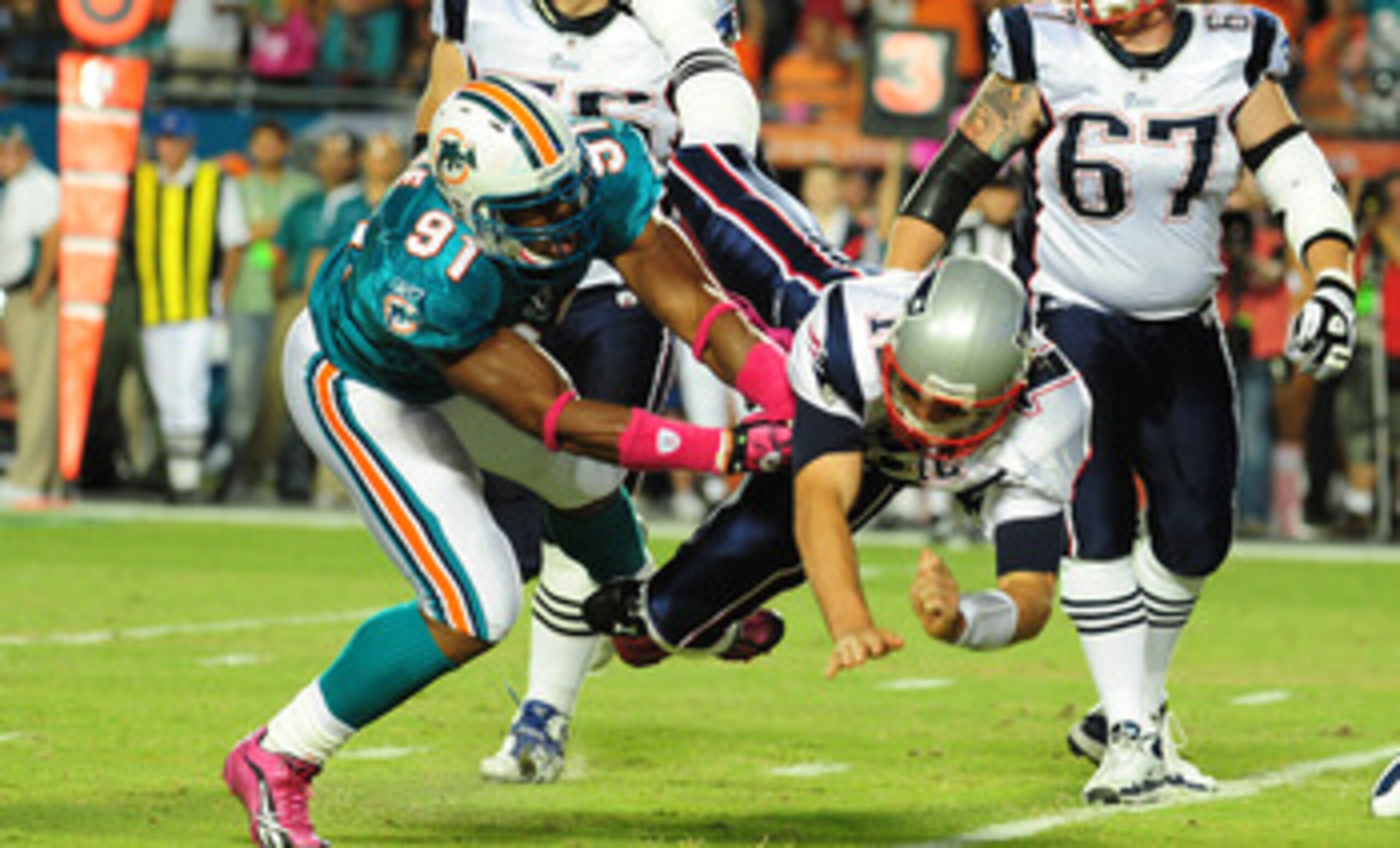 MIAMI - OCTOBER 4: Tom Brady #12 of the New England Patriots is hit after he passes by Cameron Wake #91 of the Miami Dolphins at Sun Life Field on October 4, 2010 in Miami, Florida. (Photo by Scott Cunningham/Getty Images)