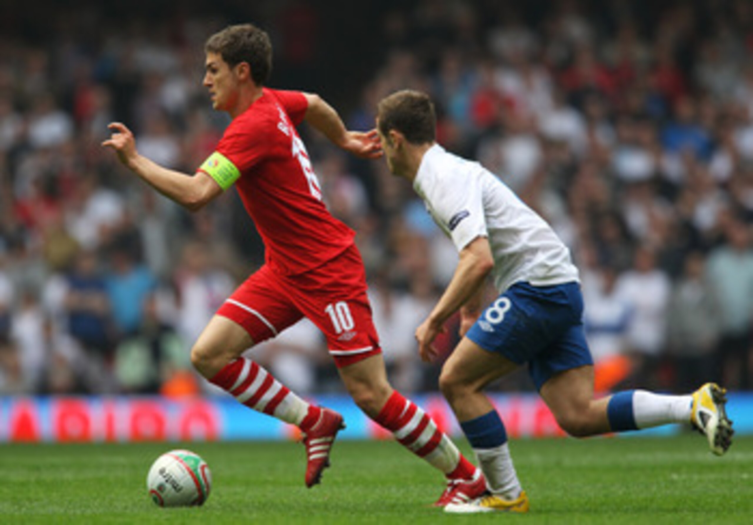 CARDIFF, WALES - MARCH 26: Aaron Ramsey of Wales takes the ball past Jack Wilshere of England during the UEFA EURO 2012 Group G qualifying match between Wales and England at the Millennium Stadium on March 26, 2011 in Cardiff, Wales.  (Photo by Alex Lives
