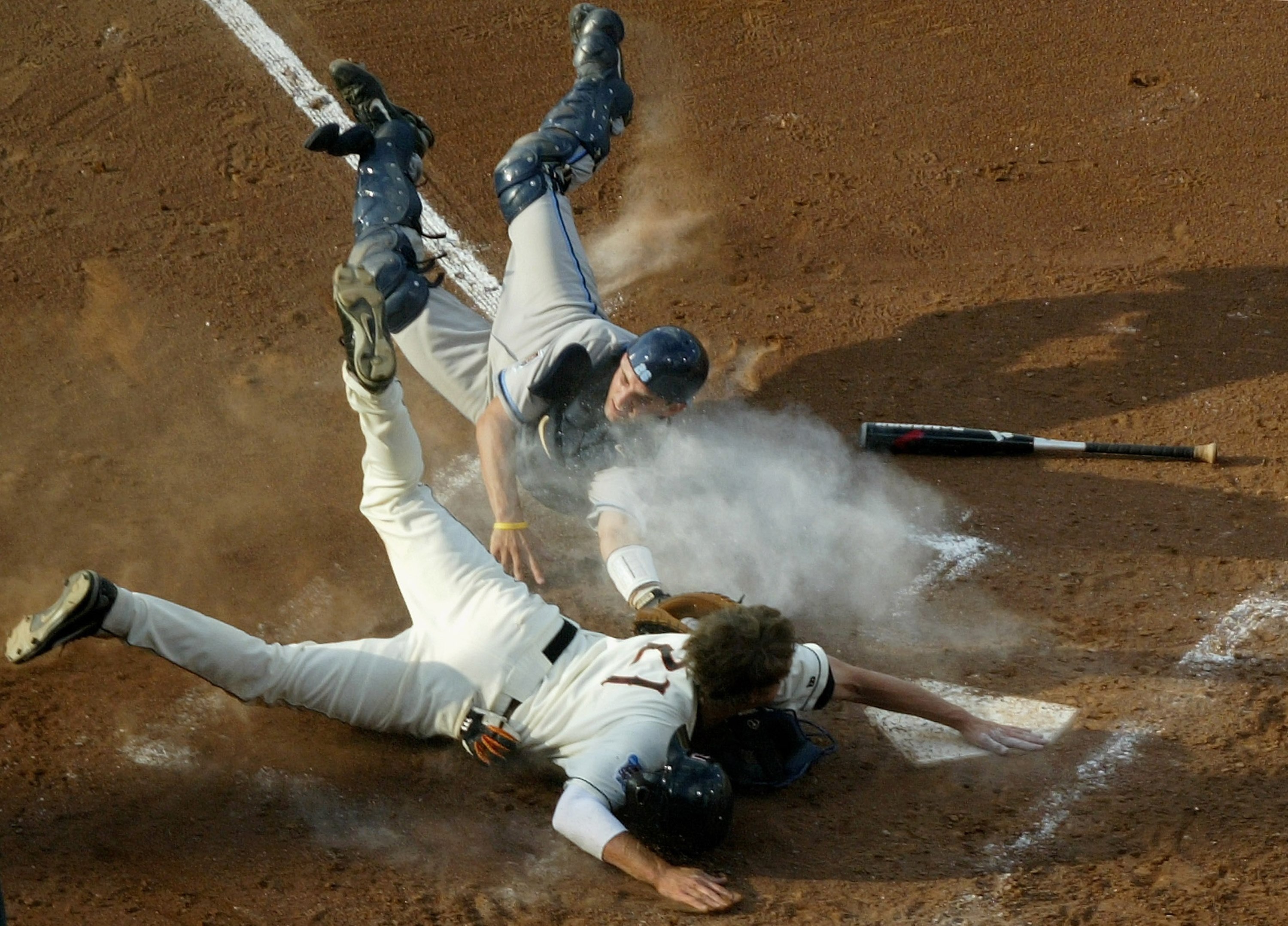 OMAHA, NE - JUNE 26:  Tyler Graham #21 of the Oregon State Beavers is safe at home ahead of a late tag by catcher Benji Johnson #26 of the North Carolina Tar Heels as he scored the first run of the game in the fourth inning after a throwing error by pitch
