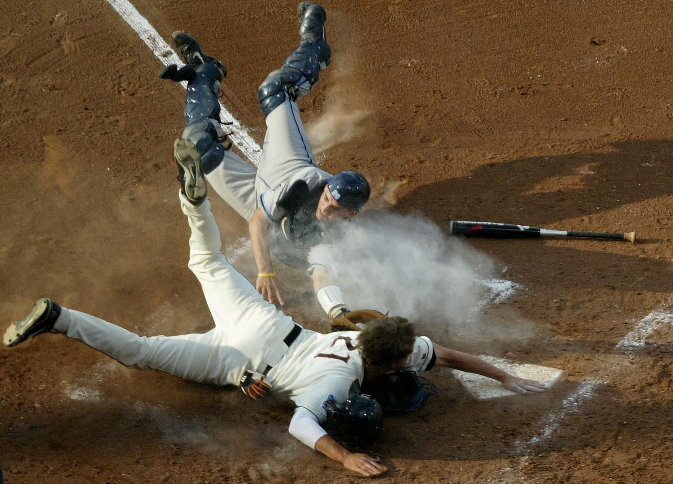 OMAHA, NE - JUNE 26:  Tyler Graham #21 of the Oregon State Beavers is safe at home ahead of a late tag by catcher Benji Johnson #26 of the North Carolina Tar Heels as he scored the first run of the game in the fourth inning after a throwing error by pitch