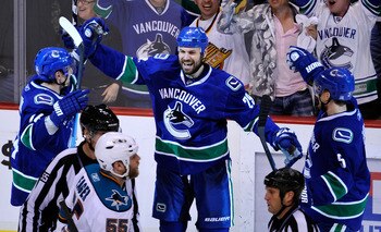 VANCOUVER, CANADA - MAY 18:  Aaron Rome #29 of the Vancouver Canucks celebrates his third period goal with teammates Alex Burrows #14 and Christian Ehrhoff #5 as Ben Eager #55 of the San Jose Sharks skates by in Game Two of the Western Conference Finals d
