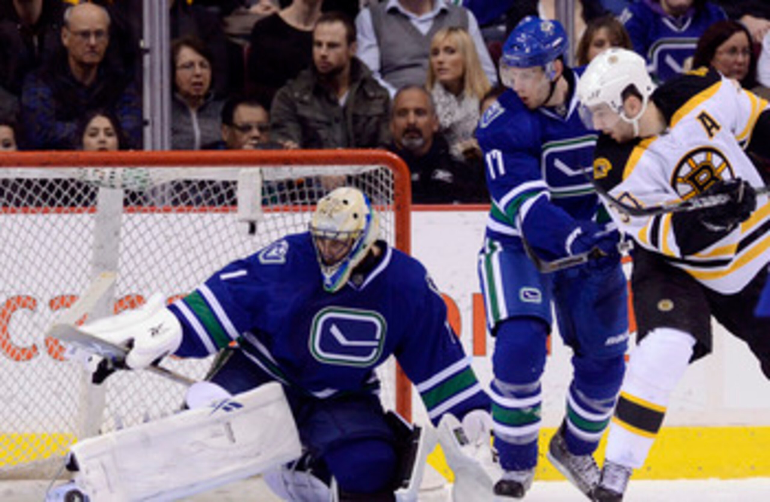 VANCOUVER, CANADA - FEBRUARY 26: Goalie Roberto Luongo #1 of the Vancouver Canucks makes a pad save while Ryan Kesler #17 of the Vancouver Canucks and Patrice Bergeron #37 of the Boston Bruins look on during the second period in NHL action on February 26,