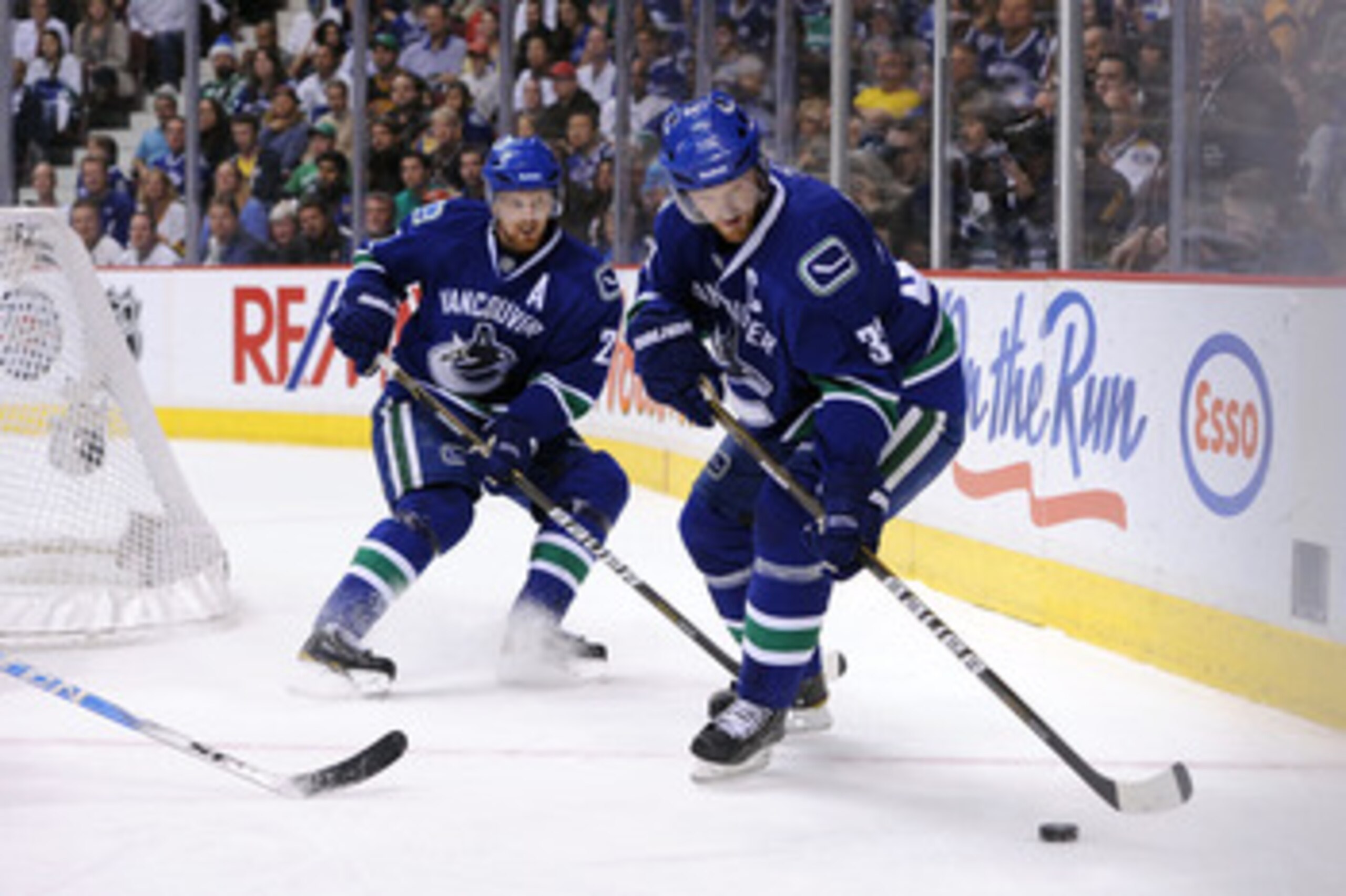 VANCOUVER, CANADA - MAY 24:  Henrik Sedin #33 of the Vancouver Canucks controls the puck as teammate Daniel Sedin #22 looks on in Game Five of the Western Conference Finals against the San Jose Sharks during the 2011 Stanley Cup Playoffs at Rogers Arena o