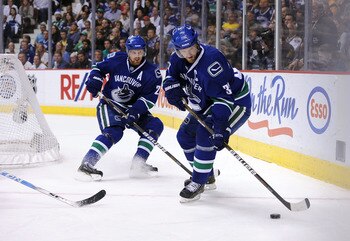 VANCOUVER, CANADA - MAY 24:  Henrik Sedin #33 of the Vancouver Canucks controls the puck as teammate Daniel Sedin #22 looks on in Game Five of the Western Conference Finals against the San Jose Sharks during the 2011 Stanley Cup Playoffs at Rogers Arena o