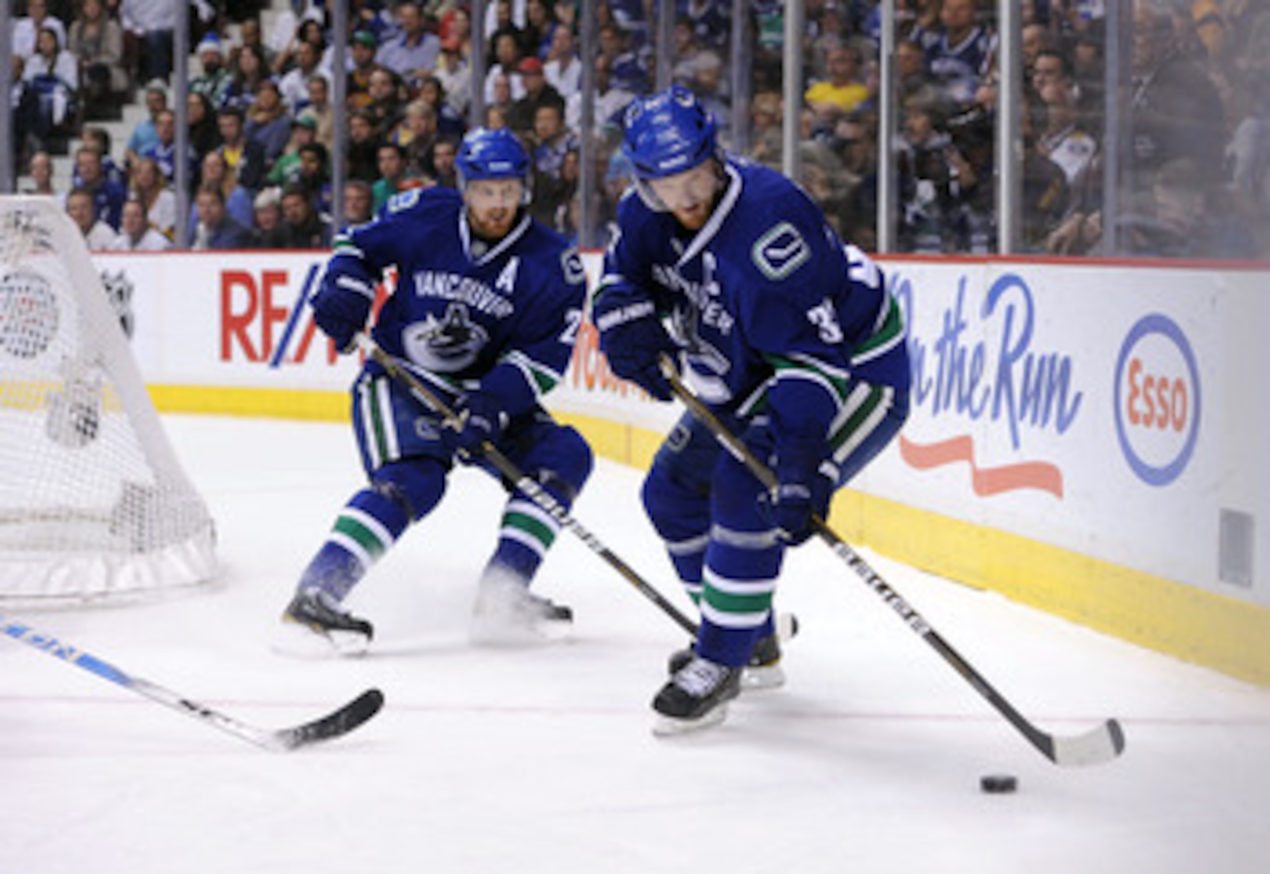 VANCOUVER, CANADA - MAY 24:  Henrik Sedin #33 of the Vancouver Canucks controls the puck as teammate Daniel Sedin #22 looks on in Game Five of the Western Conference Finals against the San Jose Sharks during the 2011 Stanley Cup Playoffs at Rogers Arena o