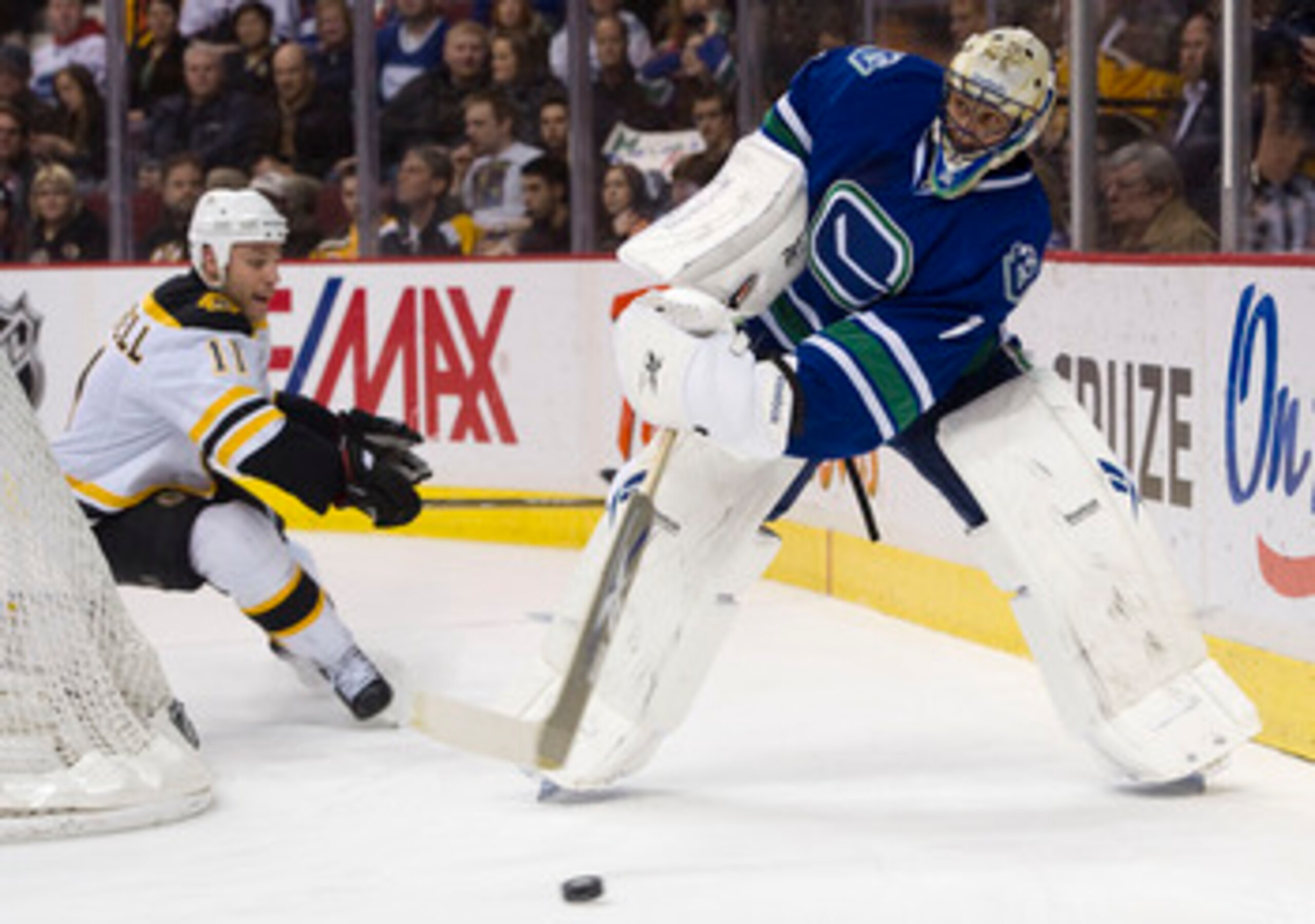 VANCOUVER, CANADA - FEBRUARY 26: Goalie Roberto Luongo #1 of the Vancouver Canucks plays the puck ahead of Gregory Campbell #11 of the Boston Bruins during the first period in NHL action on February 26, 2011 at Rogers Arena in Vancouver, British Columbia,