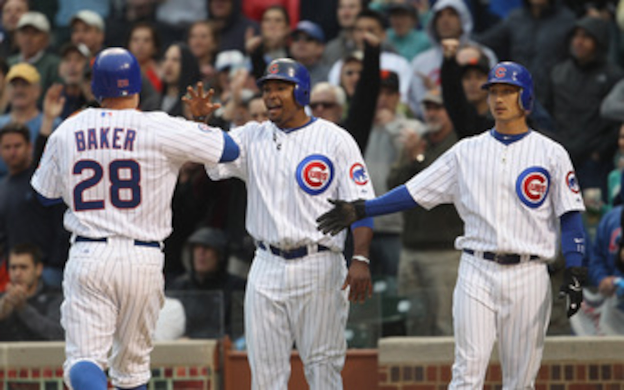 CHICAGO, IL - MAY 13: Marlon Byrd #24 (C) and Darwin Barney #15 of the Chicago Cubs greet teammate Jeff Baker #28 after scoring runs in the 7th inning against the San Francisco Giants at Wrigley Field on May 13, 2011 in Chicago, Illinois. The Cubs defeate