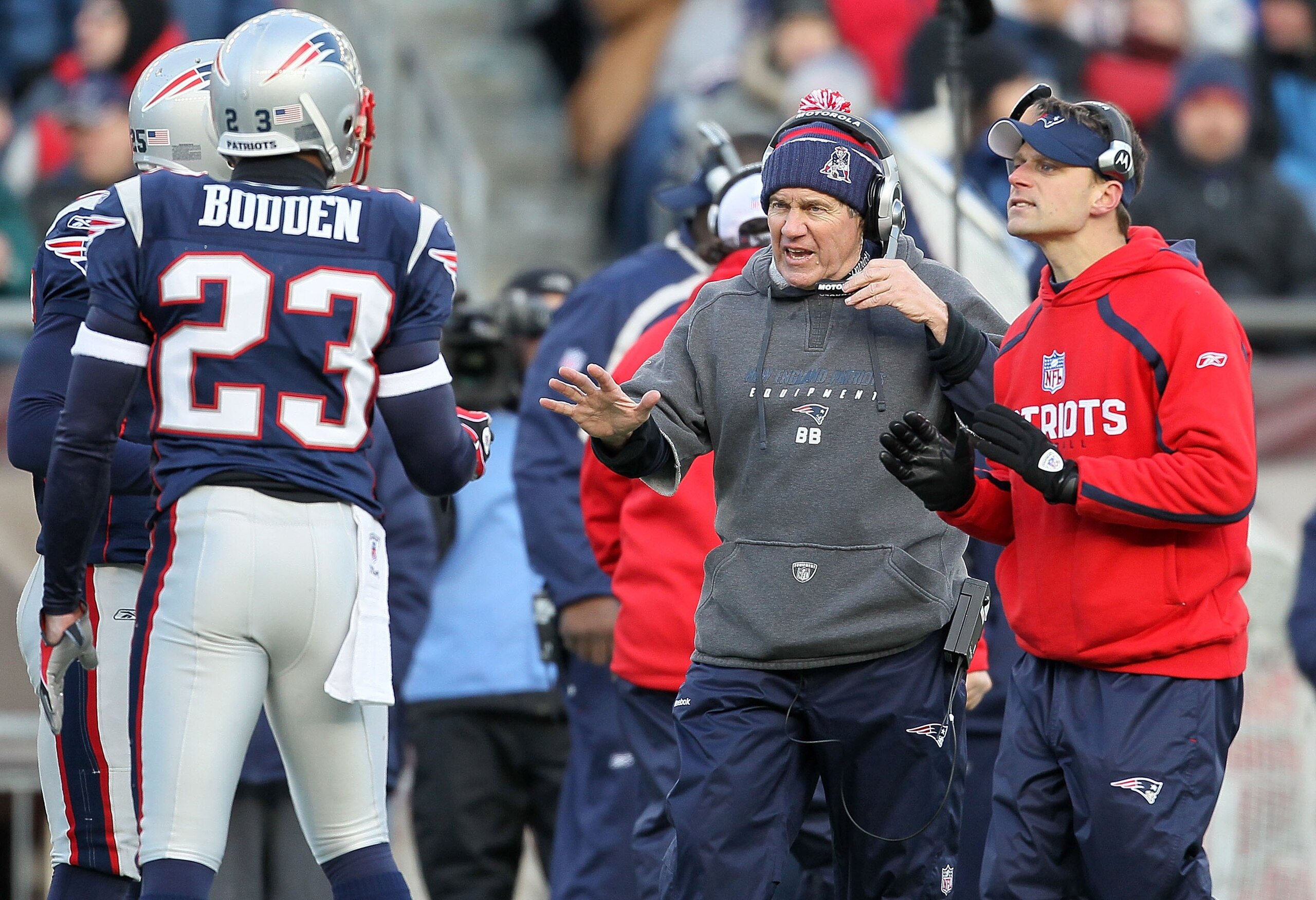 FOXBORO, MA - JANUARY 10:  Head coach Bill Belichick (C) and defensive backs coach Josh Boyer (R) of the New England Patriots talk with Leigh Bodden #23 against the Baltimore Ravens during the 2010 AFC wild-card playoff game at Gillette Stadium on January