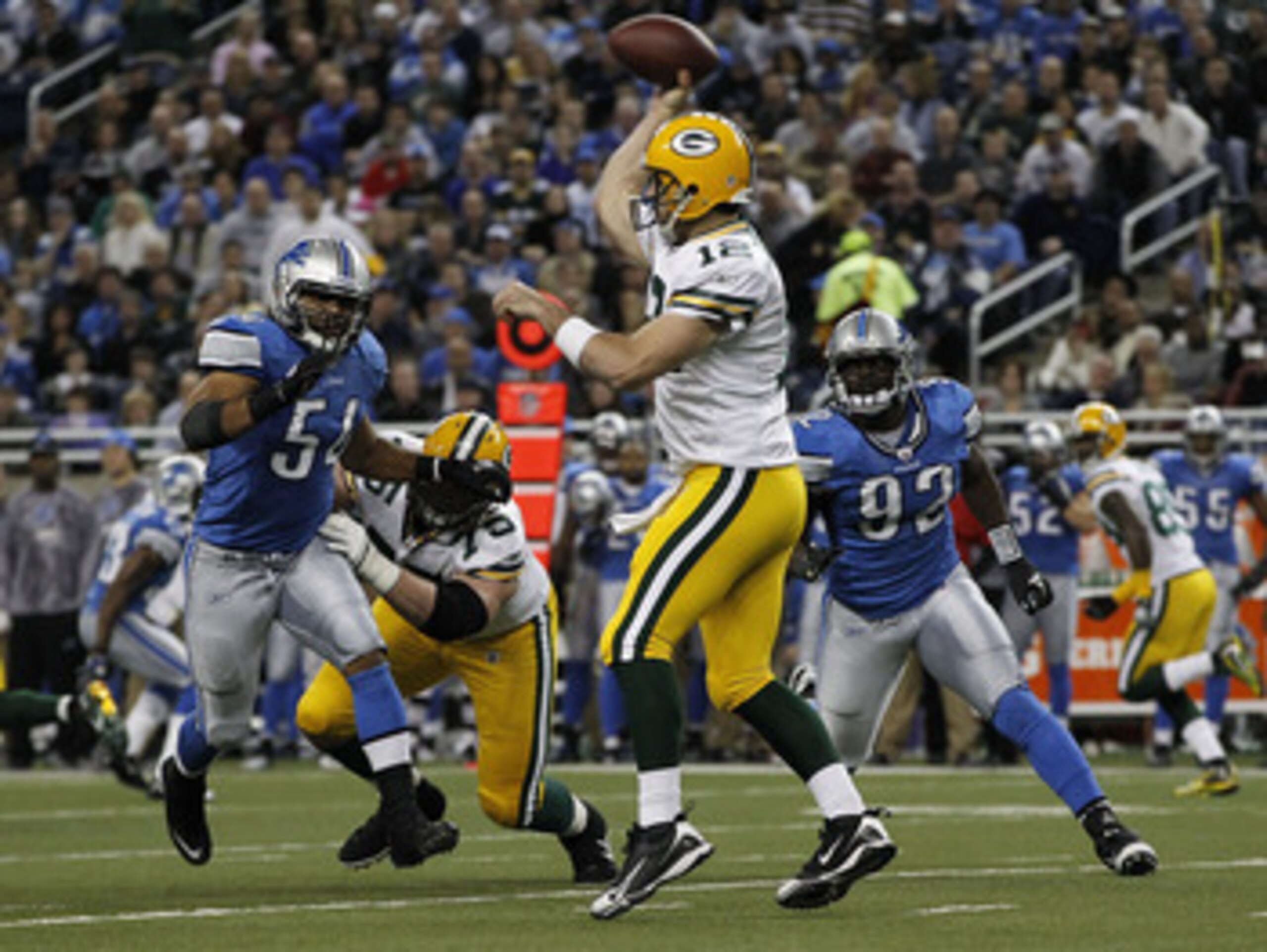 DETROIT - DECEMBER 12: Aaron Rogers #12 of the Green Bay Packers drops back to pass as DeAndre Levy #54 and Cliff Avrill #92 of the Detroit Lions rush the passer during the second quarter of the game against the Detroit Lions at Ford Field on December 12,