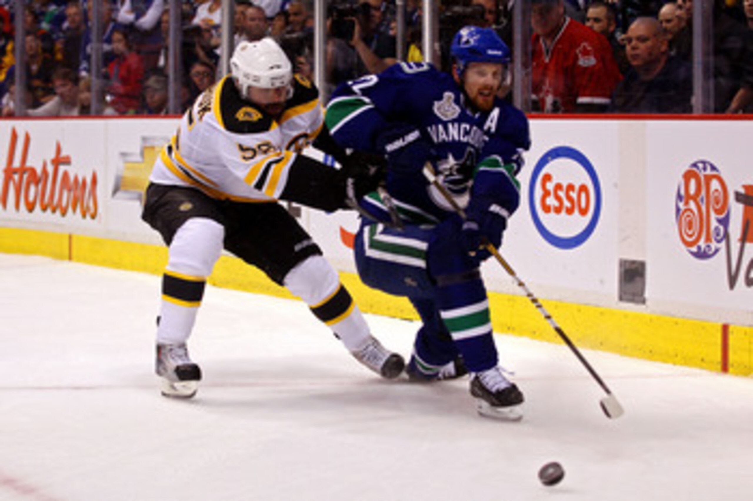 VANCOUVER, BC - JUNE 01:  Daniel Sedin #22 of the Vancouver Canucks goes for the puck against Johnny Boychuk #55 of the Boston Bruins during game one of the 2011 NHL Stanley Cup Finals at Rogers Arena on June 1, 2011 in Vancouver, Canada.  (Photo by Bruce