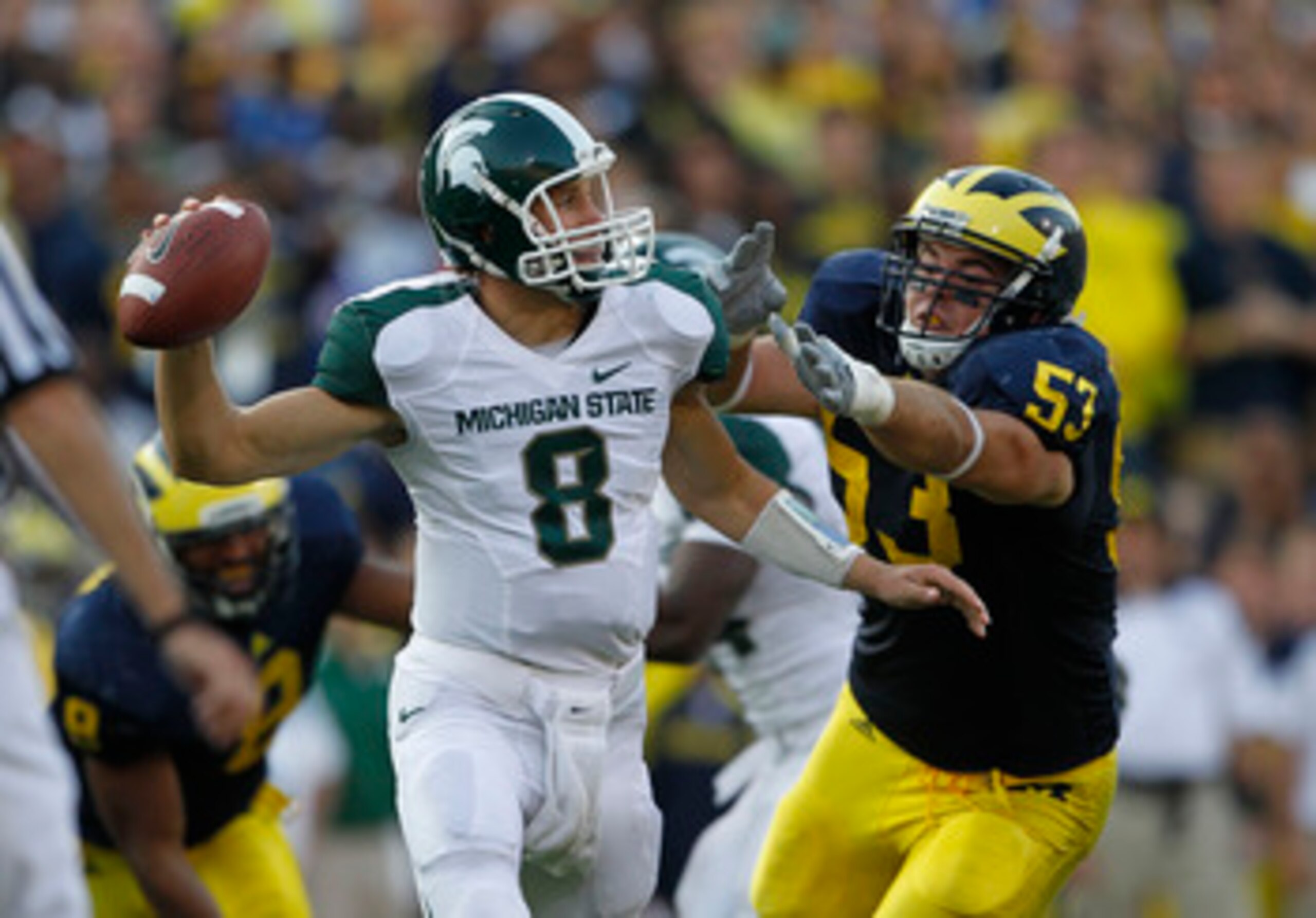 ANN ARBOR, MI - OCTOBER 09:  Kirk Cousins #8 of the Michigan State Spartans rolls out to pass as Ryan Van Bergen #53 of the Michigan Wolverines attempts to make the sack during the game on October 9, 2010 at Michigan Stadium in Ann Arbor, Michigan. The Mi