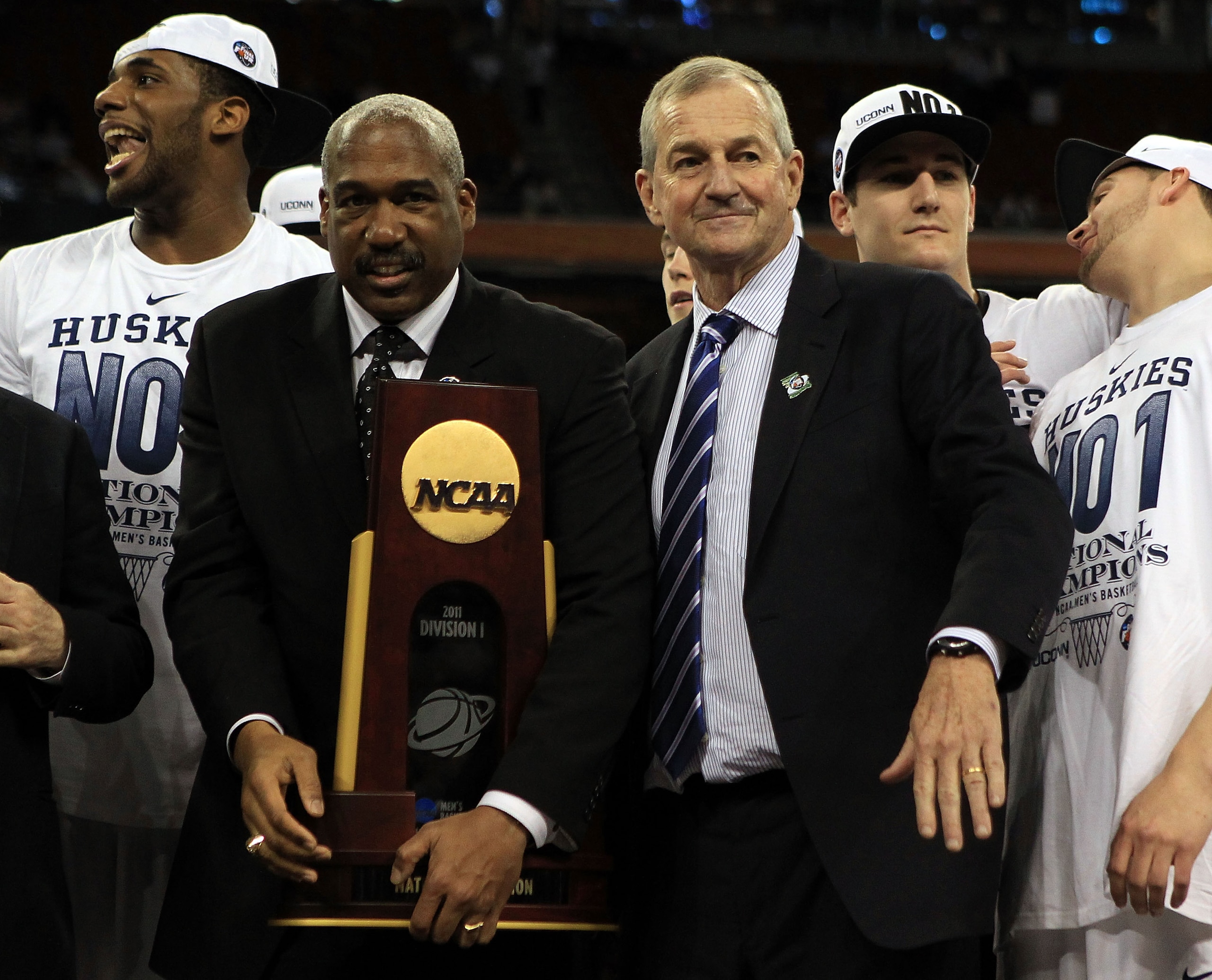 HOUSTON, TX - APRIL 04:  Athletic director Gene Smith of the Ohio State Buckeyes stands with head coach Jim Calhoun of the Connecticut Huskies as the Huskies celebrate with his team and the trophy after defeating the Butler Bulldogs to win the National Ch