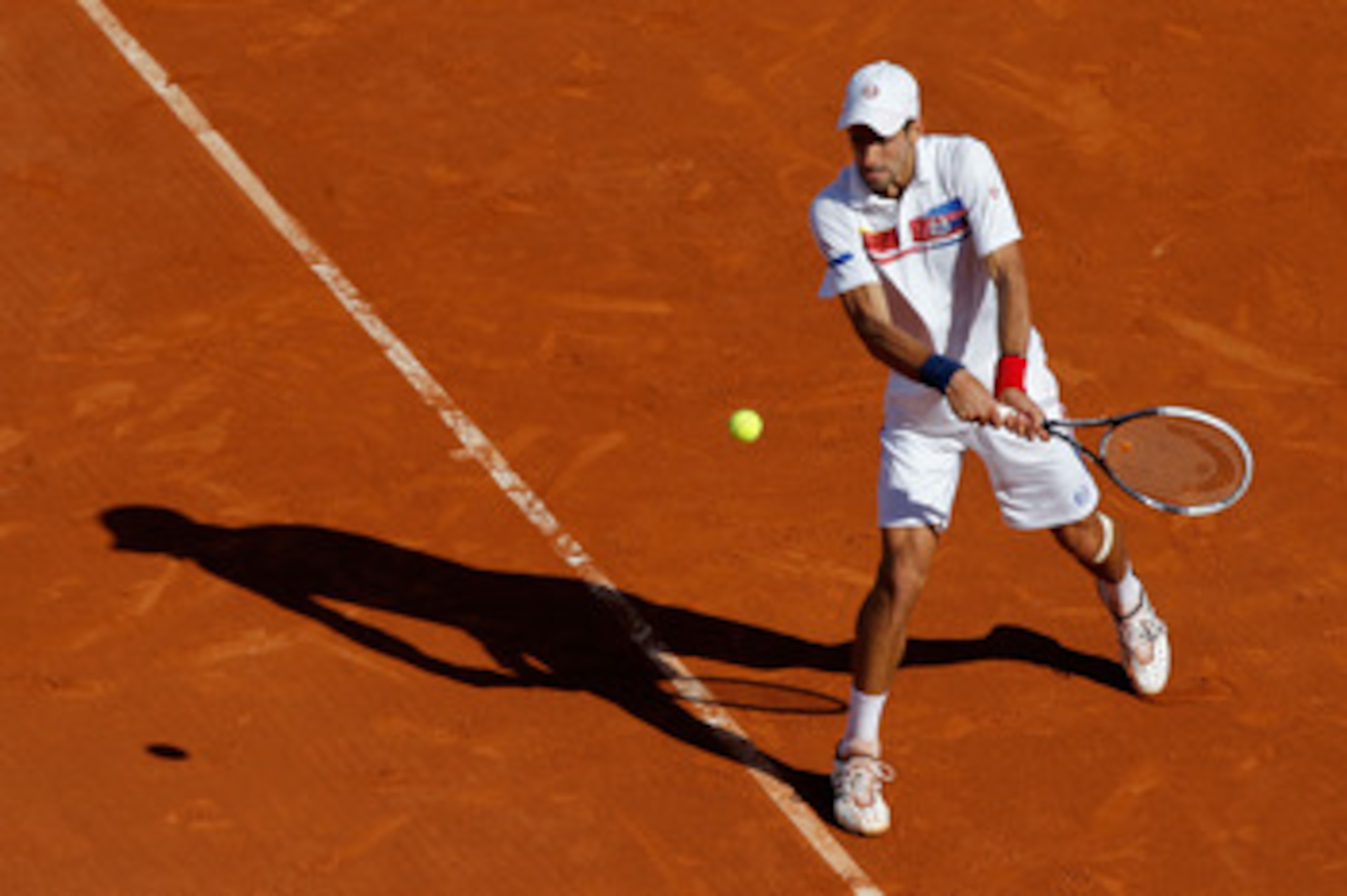 PARIS, FRANCE - MAY 29:  Novak Djokovic of Serbia hits a backhand during the men's singles round four match between Richard Gasquet of France and Novak Djokovic of Serbia on day eight of the French Open at Roland Garros on May 29, 2011 in Paris, France.  