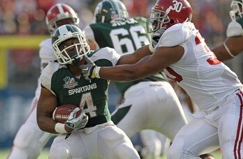 ORLANDO, FL - JANUARY 01:  Edwin Baker #4 of the Michigan State Spartans stiff arms Dont'a Hightower #30 of the Alabama Crimson Tide during the Capitol One Bowl at the Florida Citrus Bowl on January 1, 2011 in Orlando, Florida.  (Photo by Mike Ehrmann/Get