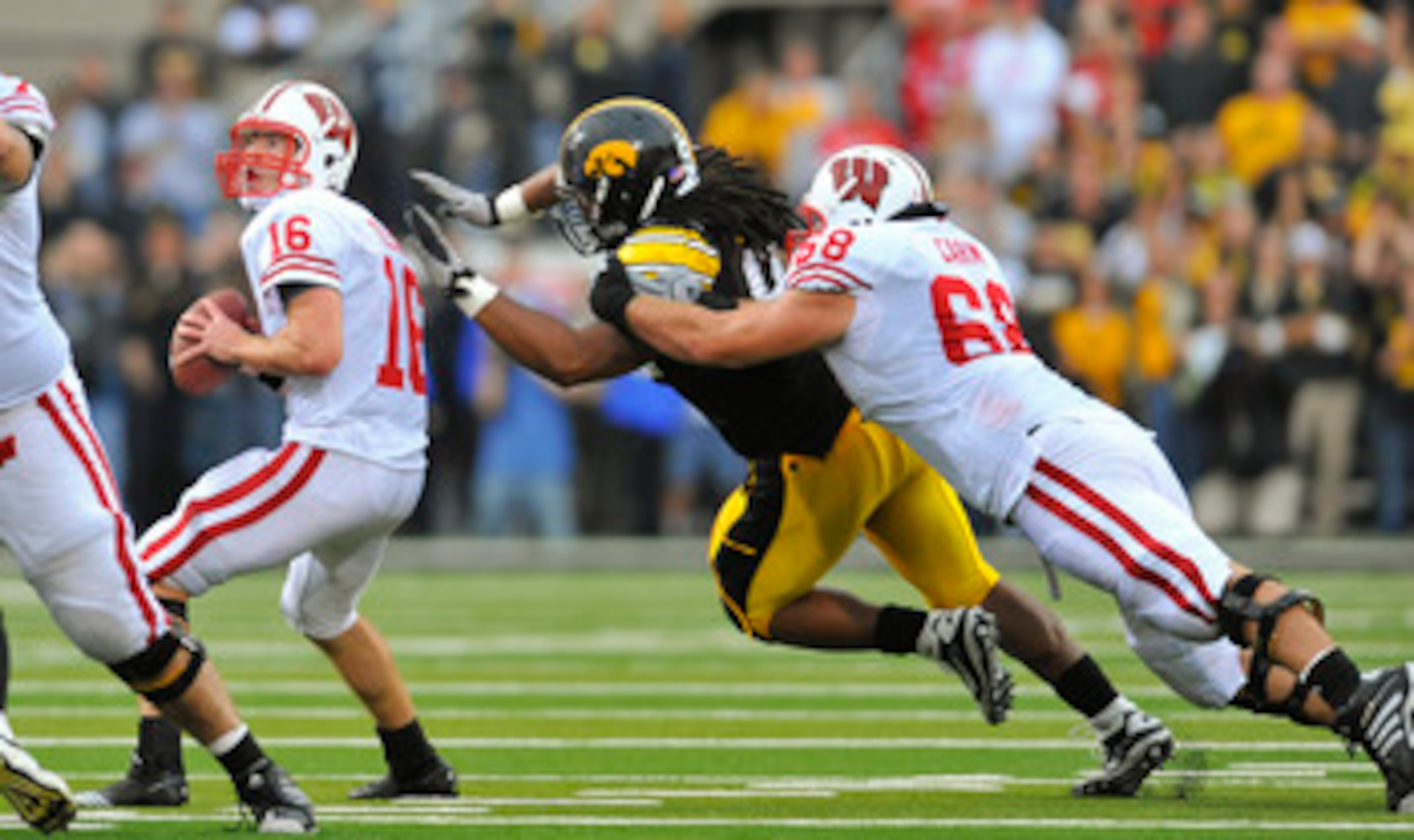 IOWA CITY, IA - OCTOBER 23- Quarterback Scott Tolzien #16 of the Wisconsin Badgers throws under pressure from Defensive lineman Adrian Clayborn #94 of the University of Iowa Hawkeyes as offensive lineman Gabe Carimi #68 defends during the first half of pl