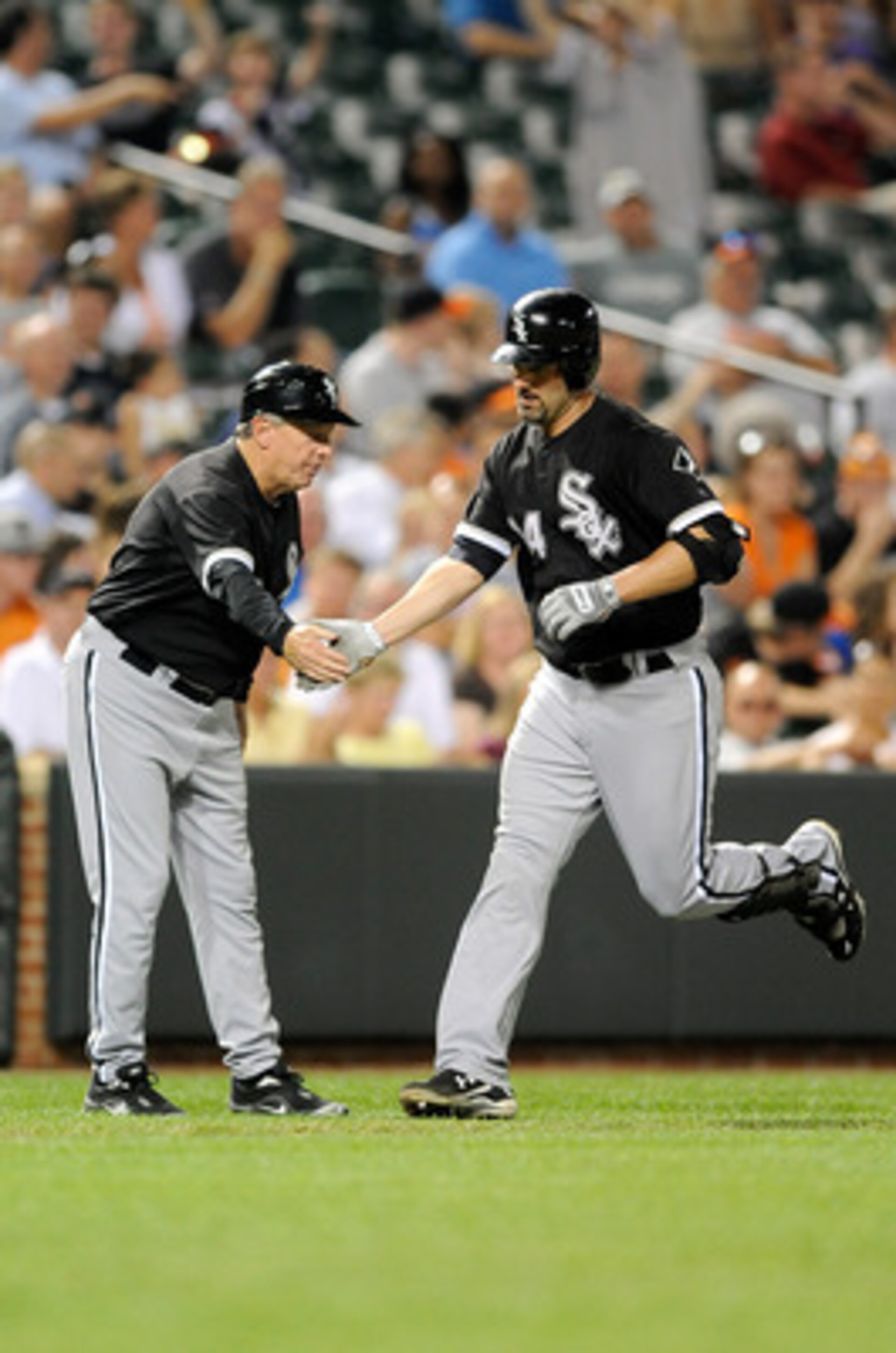 BALTIMORE - AUGUST 09:  Paul Konerko #14 of the Chicago White Sox is congratulated by third base coach Jeff Cox after hitting a home run in the ninth inning against the Baltimore Orioles at Camden Yards on August 9, 2010 in Baltimore, Maryland.  (Photo by