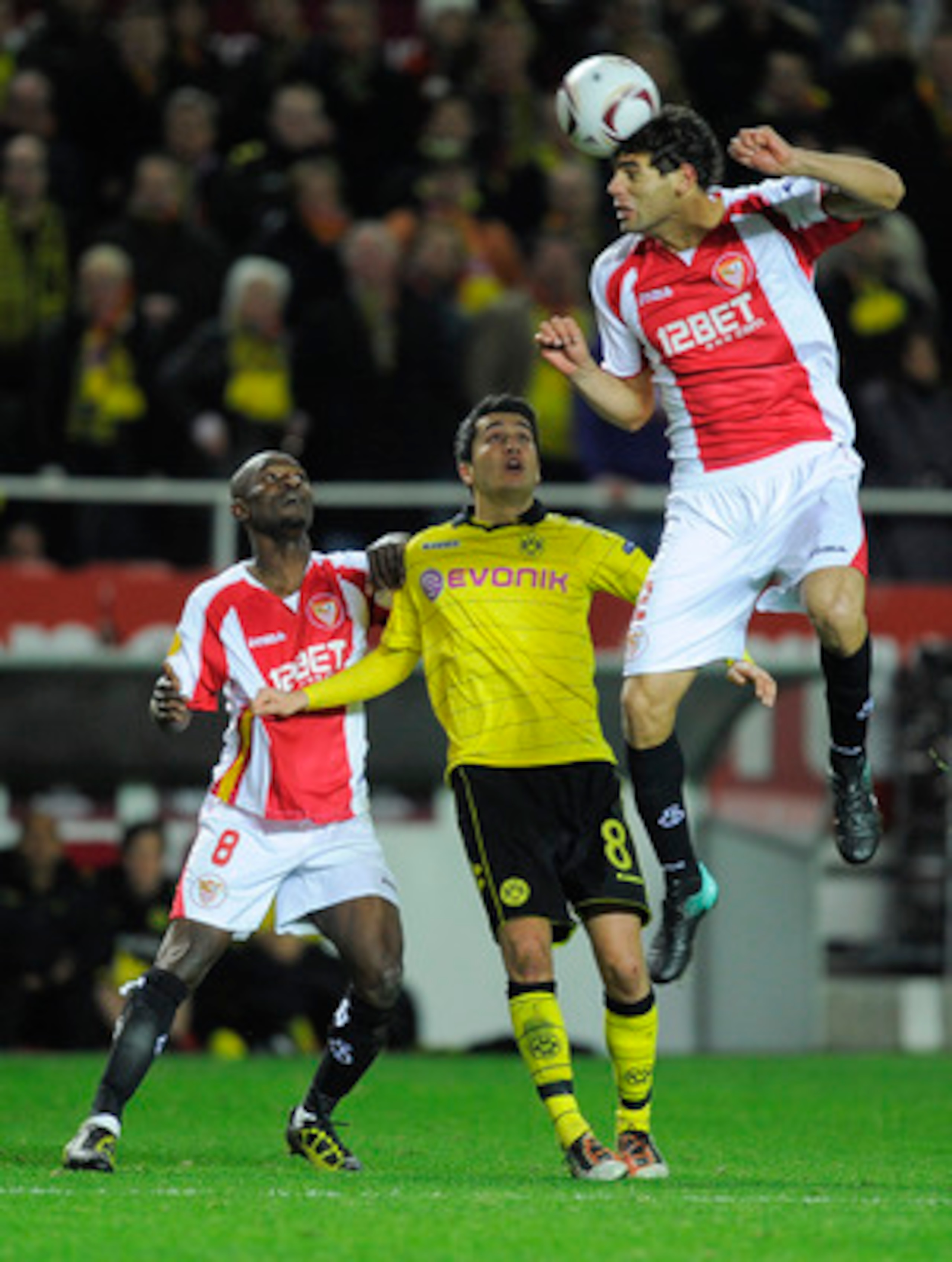 SEVILLE, SPAIN - DECEMBER 15: Nuri Sahin of Borussia Dortmund (C), Didier Zokora of Sevilla FC (L) and Federico Fazio of Sevilla FC duel for a high ball during the UEFA Europa League group J match between Sevilla and Borussia Dortmund at Estadio Ramon San