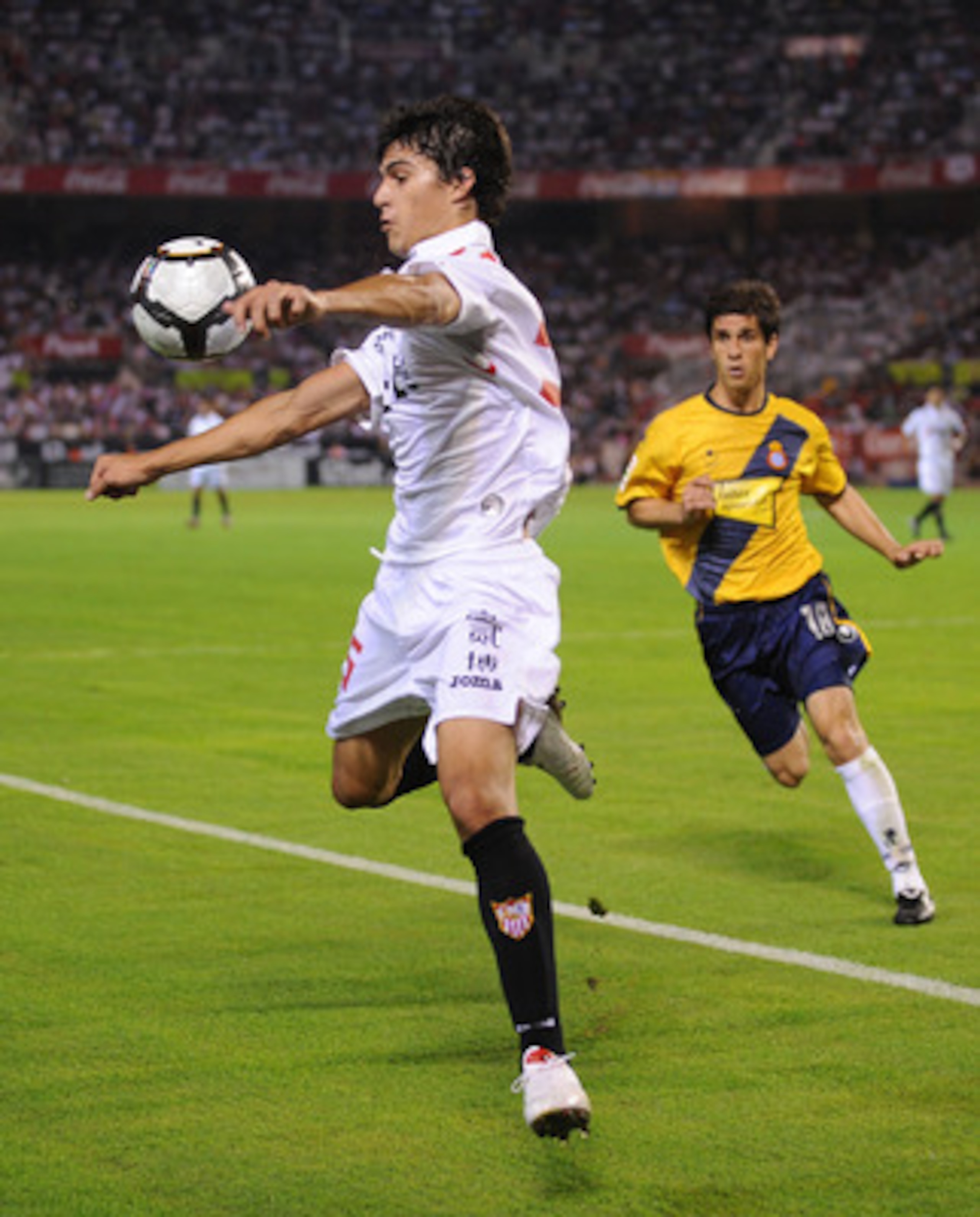 SEVILLE, SPAIN - OCTOBER 24: Diego Perotti (L) of Sevilla controls the ball while being challenged by Forlin of RCD Espanyol during the La Liga match between Espanyol and Sevilla at Estadio Ramon Sanchez Pizjuan on October 24, 2009 in Seville, Spain.  (Ph