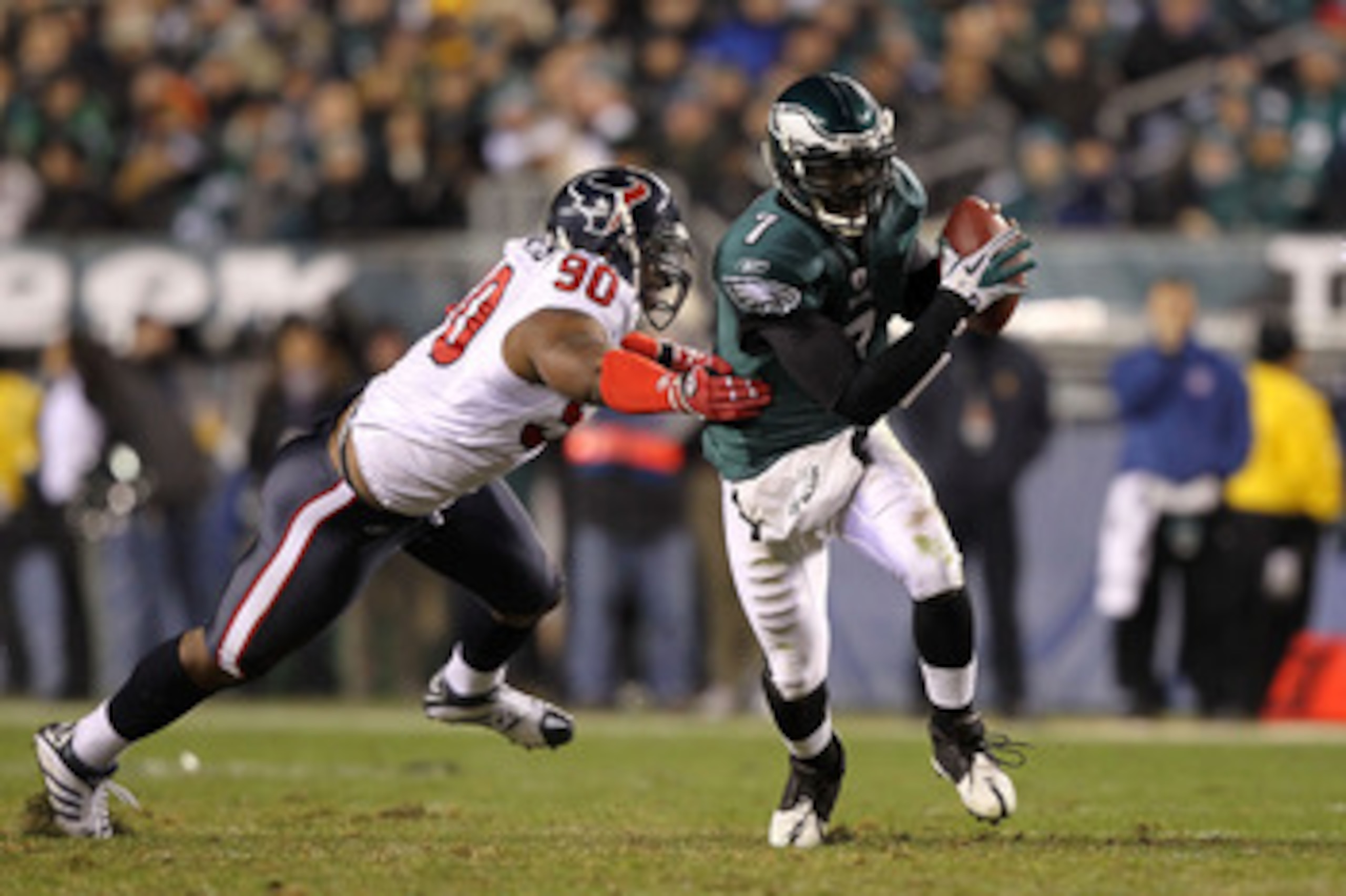 PHILADELPHIA, PA - DECEMBER 02:  Michael Vick #7 of the Philadelphia Eagles runs with the ball as he elludes the pass rush from Mario Williams #90 of the Houston Texans at Lincoln Financial Field on December 2, 2010 in Philadelphia, Pennsylvania.  (Photo 