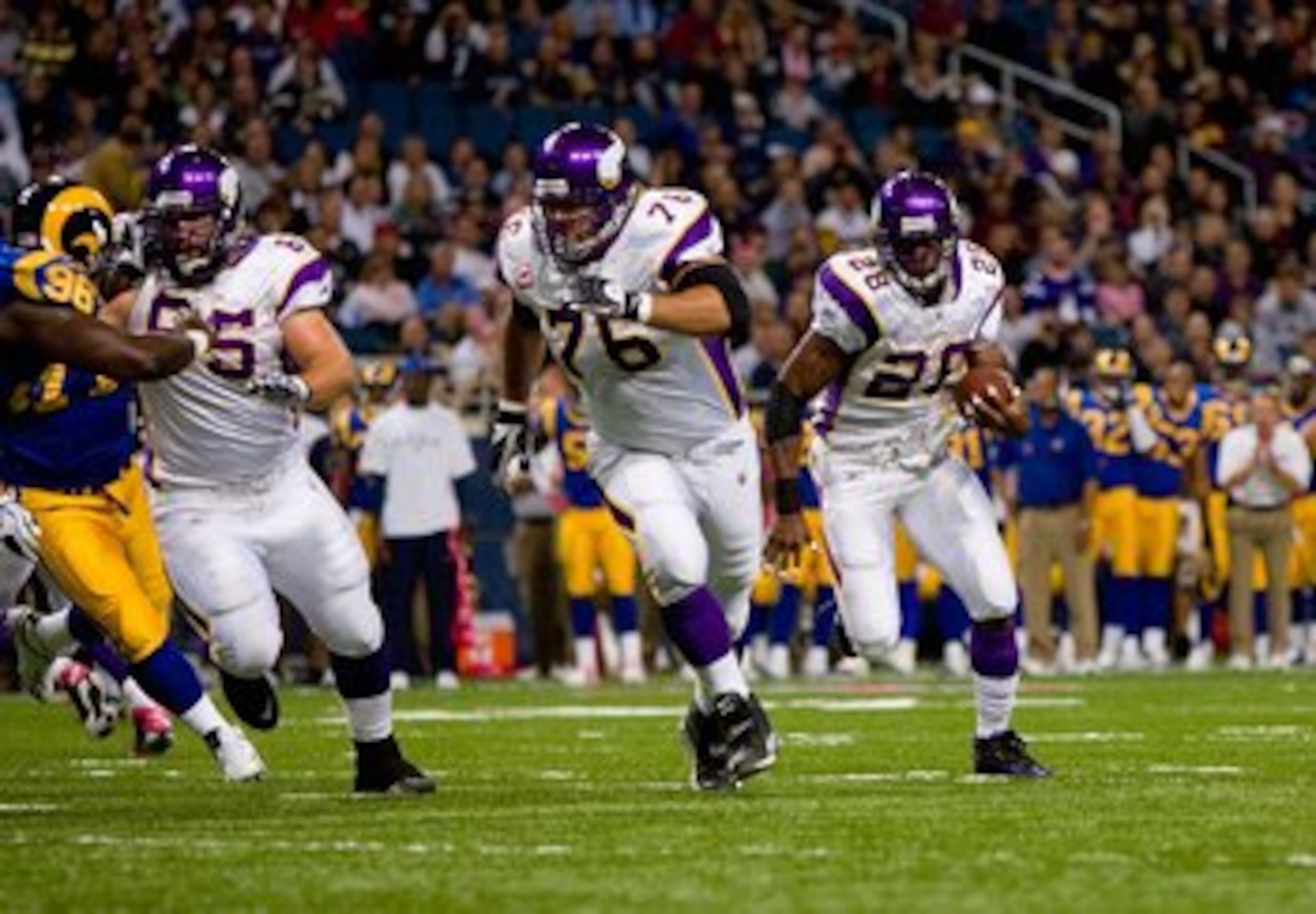 ST. LOUIS - OCTOBER 11:  Adrian Peterson #28 of the Minnesota Vikings runs to his left toward the end zone in front of teammates Steve Hutchinson #76 and John Sullivan #65 during their NFL game against the St. Louis Rams at the Edward Jones Dome on Octobe