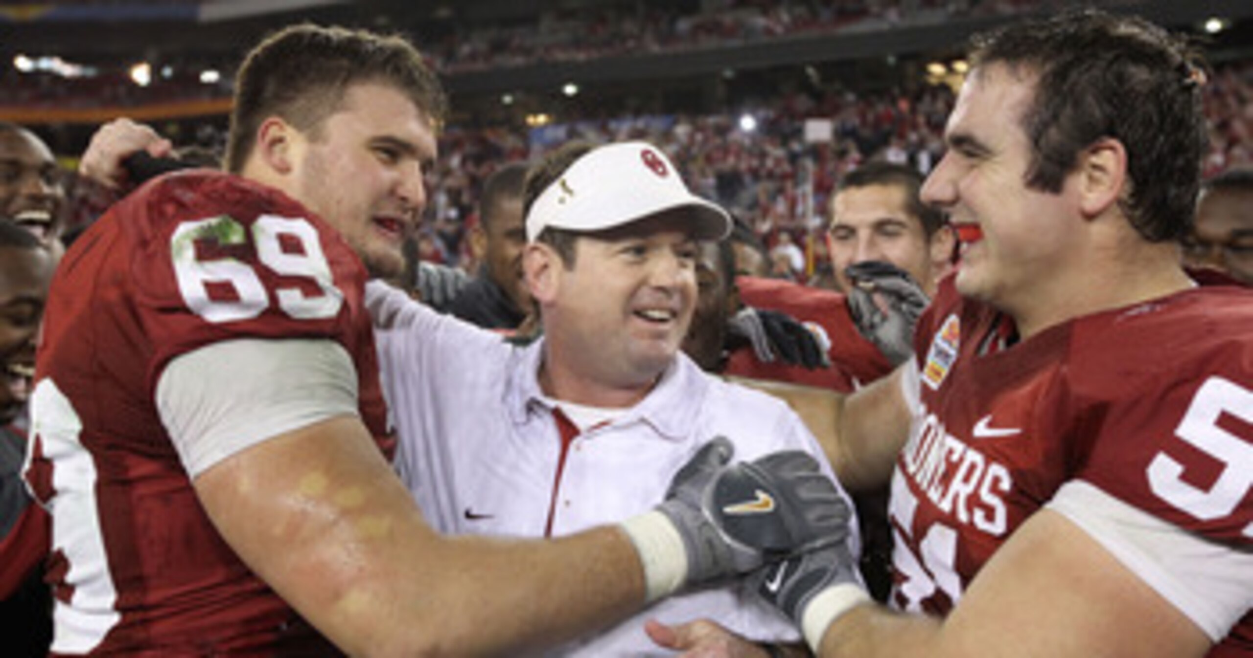 GLENDALE, AZ - JANUARY 01:  Head coach Bob Stoops is hugged by Eric Mensik #69 and Brian Lepak #51 late in the fourth quarter before the Sooners 48-20 victory against the Connecticut Huskies during the Tostitos Fiesta Bowl at the Universtity of Phoenix St