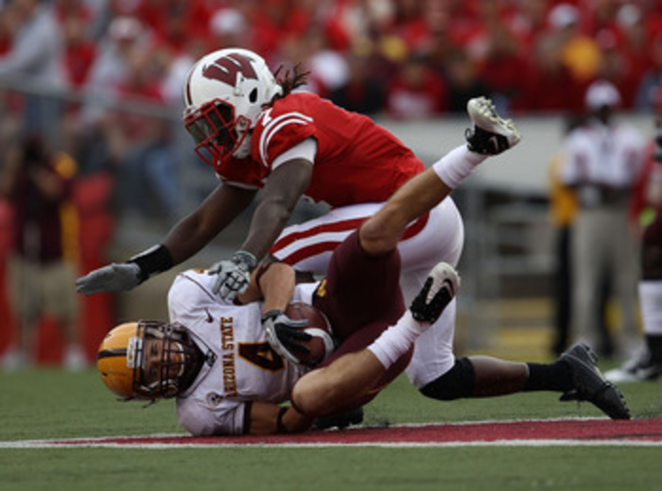 MADISON, WI - SEPTEMBER 18: Aaron Pflugrad #4 of the Arizona State Sun Devils catches a pass on the ground under pressure from Aaron Henry #7 of the Wisconsin Badgers at Camp Randall Stadium on September 18, 2010 in Madison, Wisconsin. Wisconsin defeated