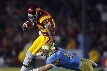 PASADENA, CA - DECEMBER 04:  Wide receiver Ronald Johnson #83 of the USC Trojans breaks a tackle by Sean Westgate #11 of the UCLA Bruins during the first half at the Rose Bowl on December 4, 2010 in Pasadena, California. USC defeated UCLA 28-14.  (Photo b