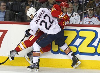CALGARY, CANADA - APRIL 6: Mark Giordano #5 of the Calgary Flames is pinned against the boards by Jean-Francois Jacques #22 of the Edmonton Oilers in first period NHL action on April 6, 2011 at the Scotiabank Saddledome in Calgary, Alberta, Canada. (Photo