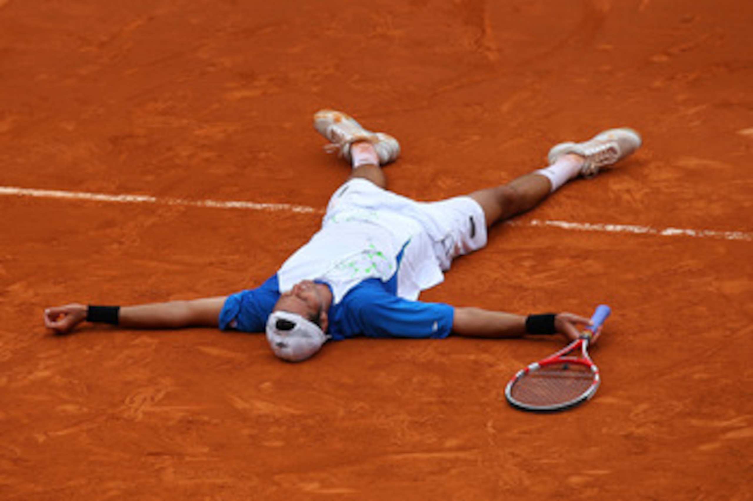 PARIS, FRANCE - MAY 30:  Juan Ignacio Chela of Argentina falls to the court as he celebrates matchpoint during the men's singles round four match between Alejandro Falla of Columbia and Juan Ignacio Chela of Argentina on day nine of the French Open at Rol