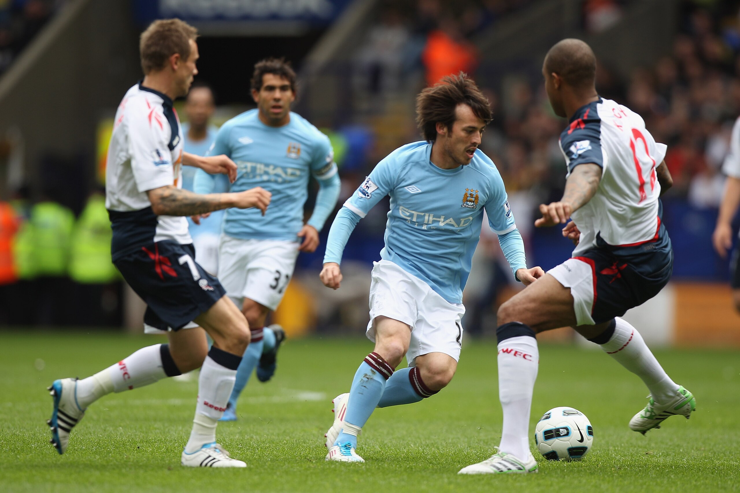 BOLTON, ENGLAND - MAY 22:  David Silva (C) of Manchester City takes on Matt Taylor (L) and Zat Knight (R) during the Barclays Premier League match between  Bolton Wanderers and Manchester City at the Reebok Stadium on May 22, 2011 in Bolton, England.  (Ph