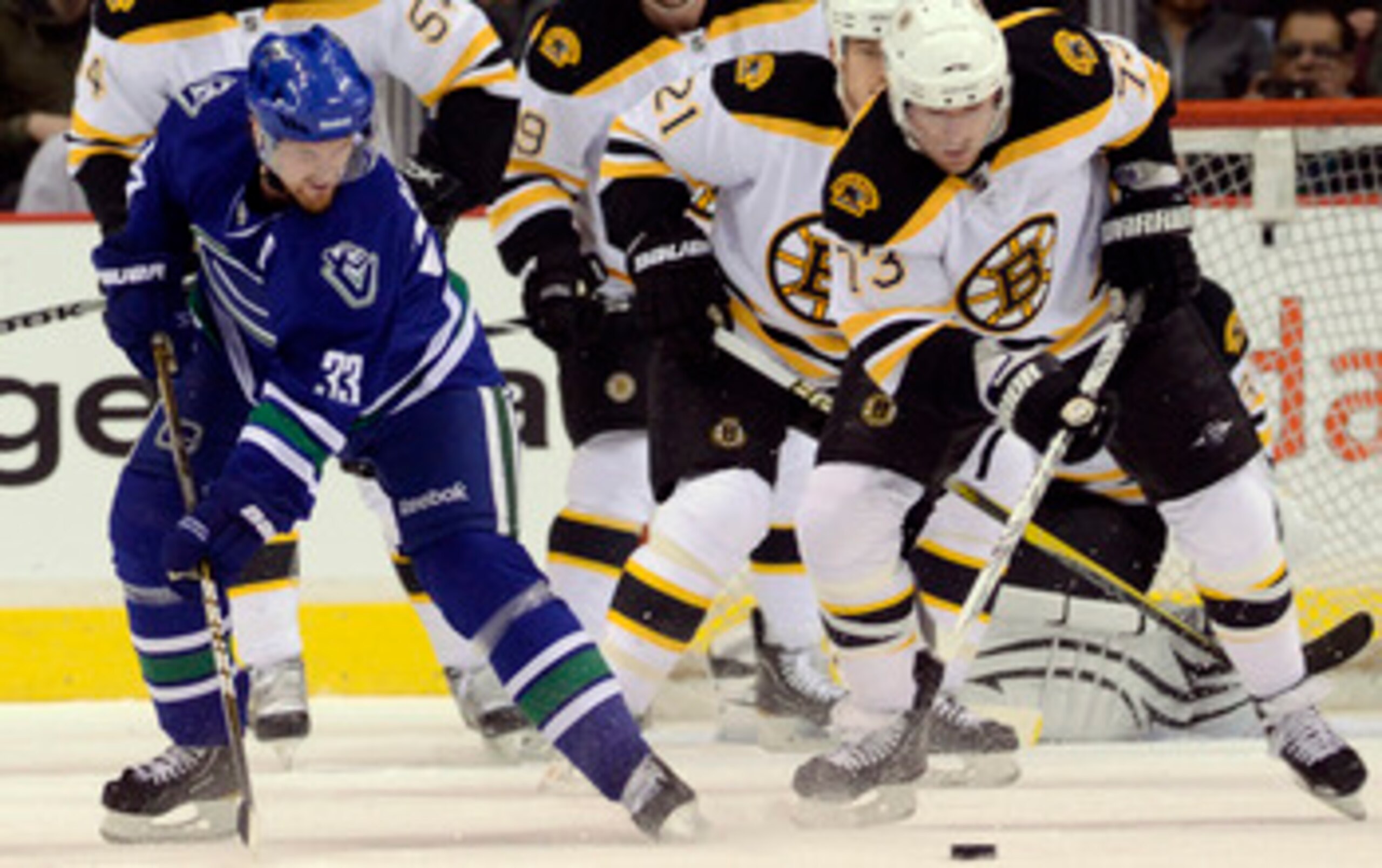 VANCOUVER, CANADA - FEBRUARY 26: Henrik Sedin #33 of the Vancouver Canucks is checked off the puck by Michael Ryder #73 of the Boston Bruins during the first period in NHL action on February 26, 2011 at Rogers Arena in Vancouver, British Columbia, Canada.
