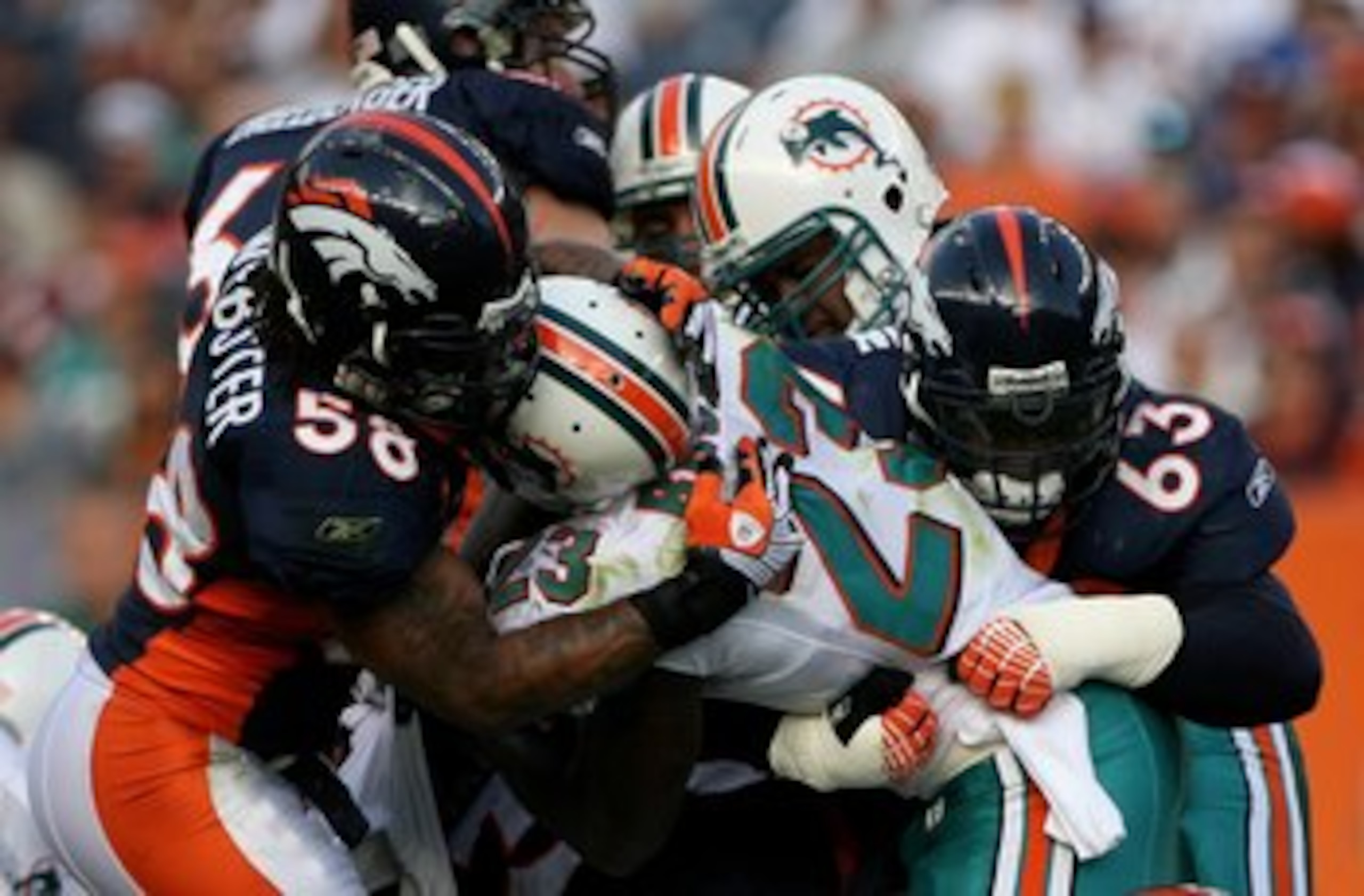 DENVER - NOVEMBER 02:  Running back Ronnie Brown #23 of the Miami Dolphins is stopped by defensive tackle Dewayne Robertson #63 and linebacker Nate Webster #58 of the Denver Broncos during NFL action at Invesco Field at Mile High on November 2, 2008 in De