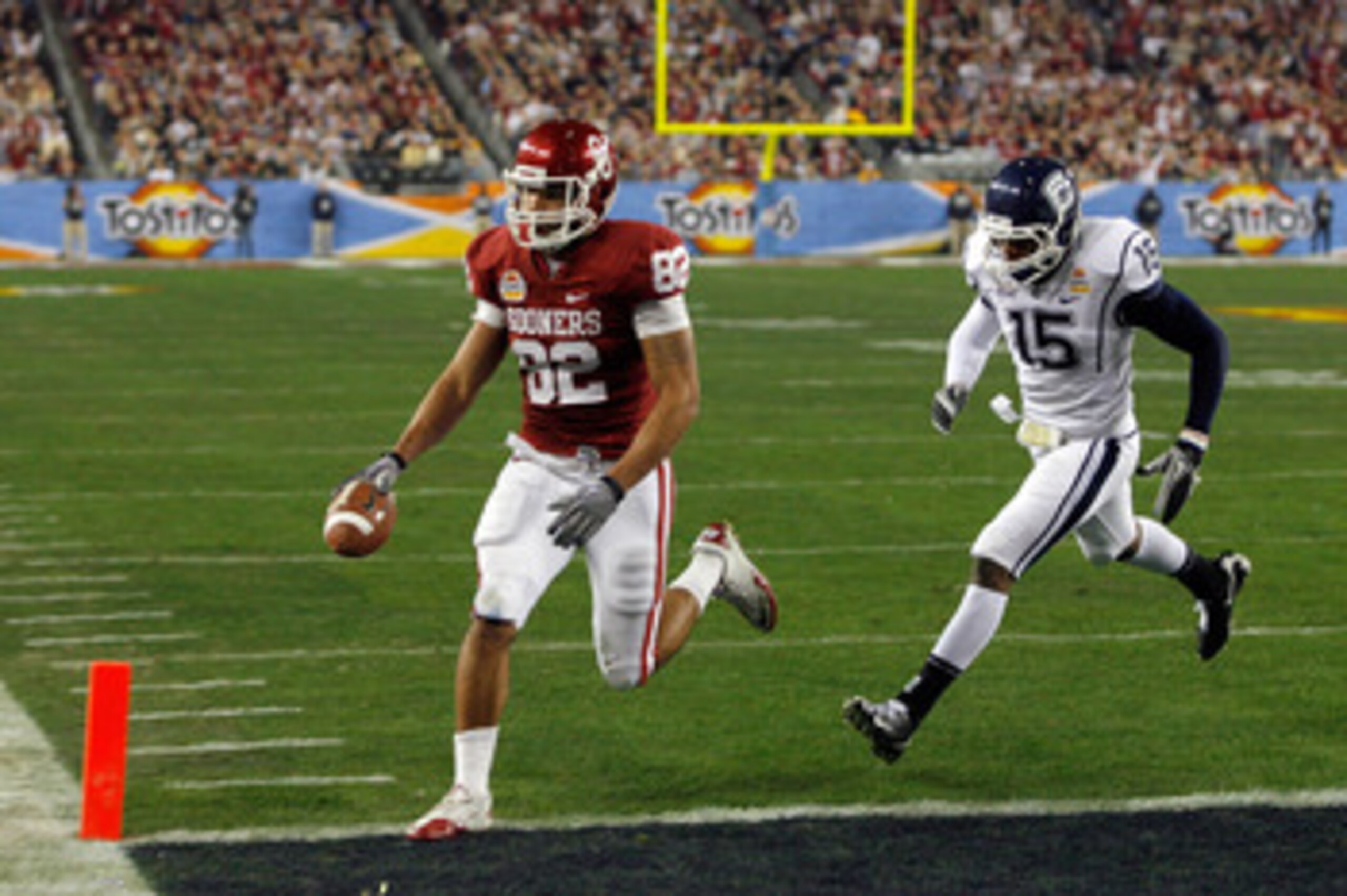 GLENDALE, AZ - JANUARY 01:  Tight end James Hanna #82 of the Oklahoma Sooners catches a touchdown pass in the first quarter past Jerome Junior #15 of the Connecticut Huskies during the Tostitos Fiesta Bowl at the Universtity of Phoenix Stadium on January