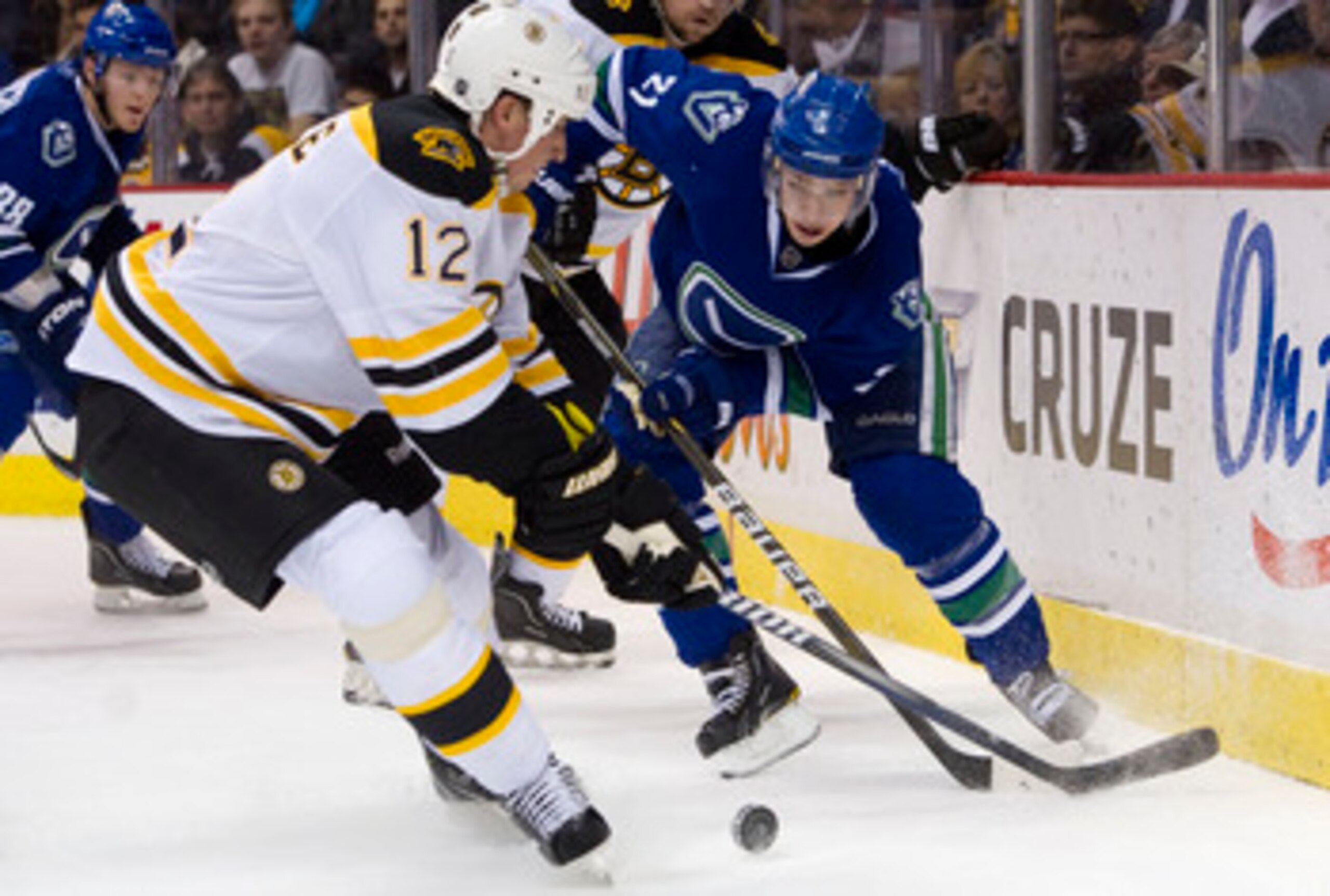 VANCOUVER, CANADA - FEBRUARY 26: Mason Raymond #21 of the Vancouver Canucks tries to chip the puck past Tomas Kaberle #12 of the Boston Bruins during the second period in NHL action on February 26, 2011 at Rogers Arena in Vancouver, British Columbia, Cana