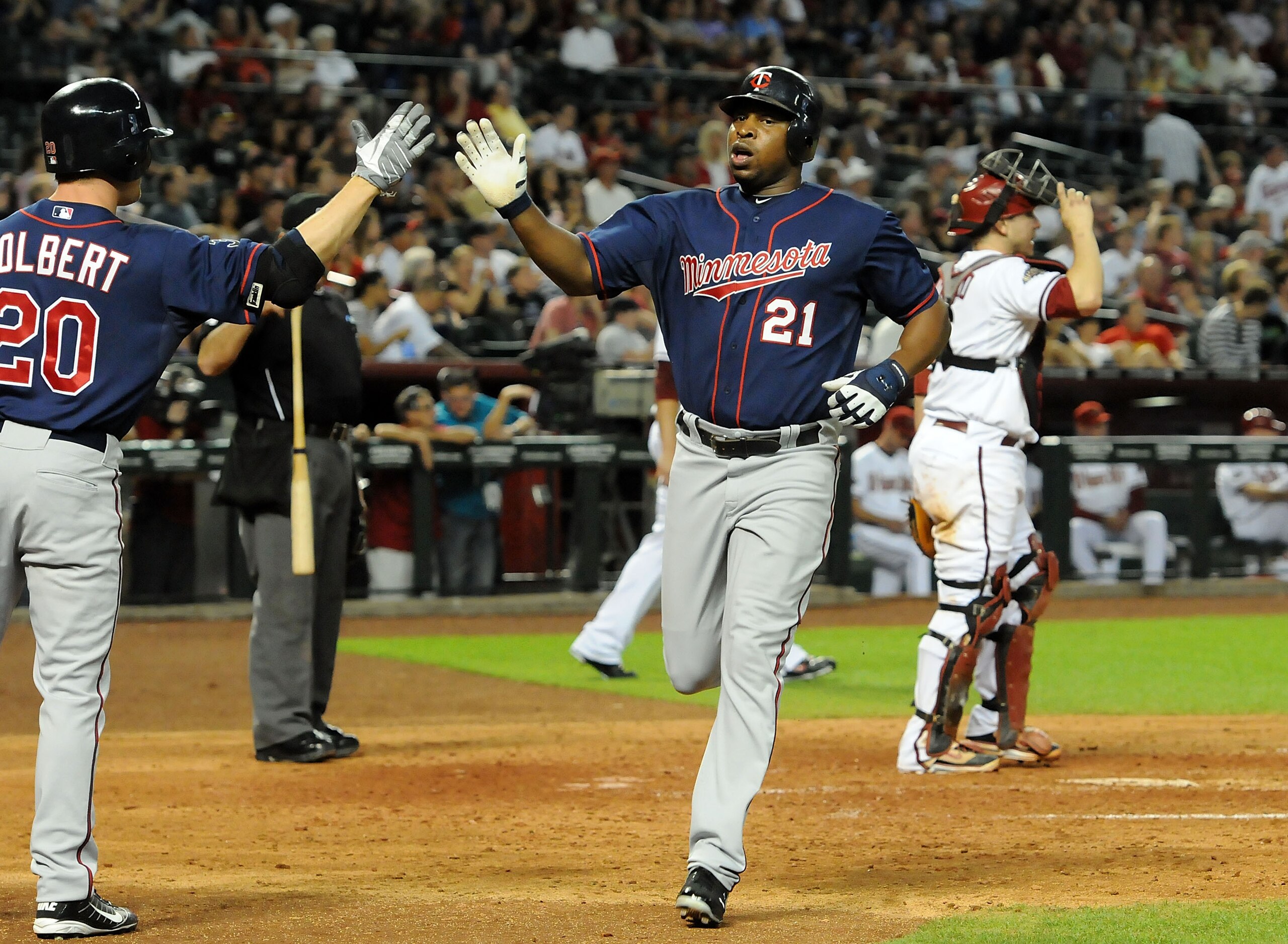 PHOENIX - MAY 20:  Delmon Young #21 of the Minnesota Twins gets a high-five from teammate Matt Tolbert #20 after scoring against the Arizona Diamondbacks at Chase Field on May 20, 2011 in Phoenix, Arizona.  (Photo by Norm Hall/Getty Images)