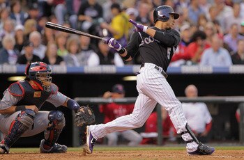DENVER, CO - MAY 27:  Carlos Gonzalez #5 of the Colorado Rockies hits an RBI single to score Eric Young of the Rockies as catcher Yadier Molina #4 of the St. Louis Cardinals backs up the plate in the third inning at Coors Field on May 27, 2011 in Denver, 