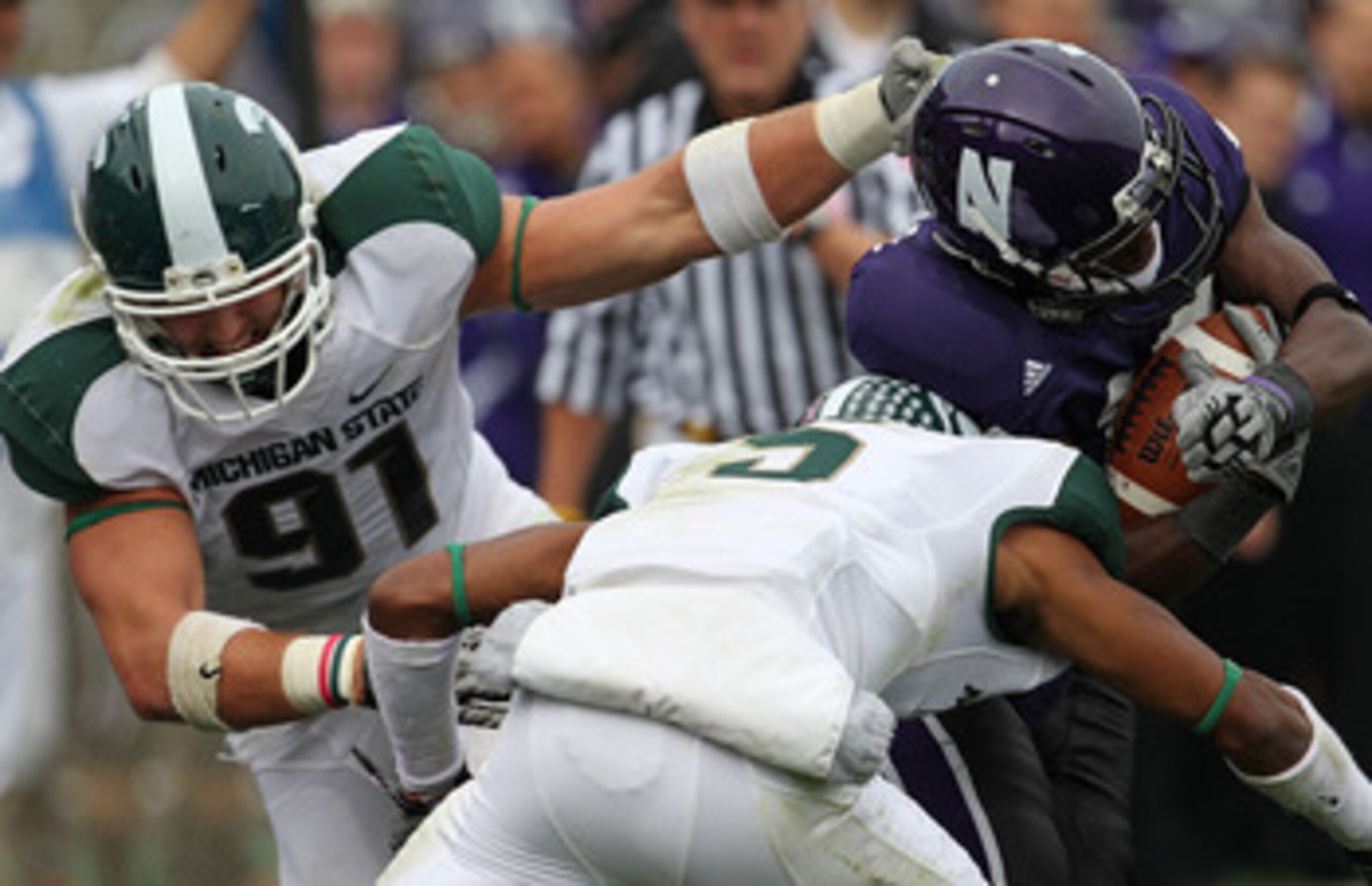 EVANSTON, IL - OCTOBER 23: Johnny Adams #5 and Tyler Hoover #91 of the Michigan State Spartans bring down Rashad Lawrence #17 of the Northwestern Wildcats at Ryan Field on October 23, 2010 in Evanston, Illinois. Michigan State defeated Northwestern 35-27.