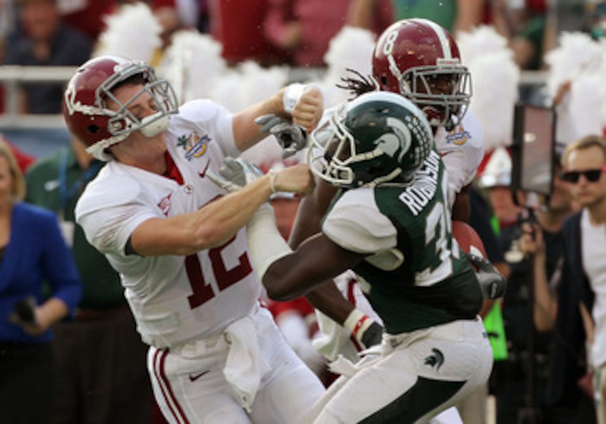 ORLANDO, FL - JANUARY 01:  Greg McElroy #12 of the Alabama Crimson Tide blocks Trenton Robinson #39 of  the Michigan State Spartans on a touchdown run during the Capitol One Bowl at the Florida Citrus Bowl on January 1, 2011 in Orlando, Florida.  (Photo b