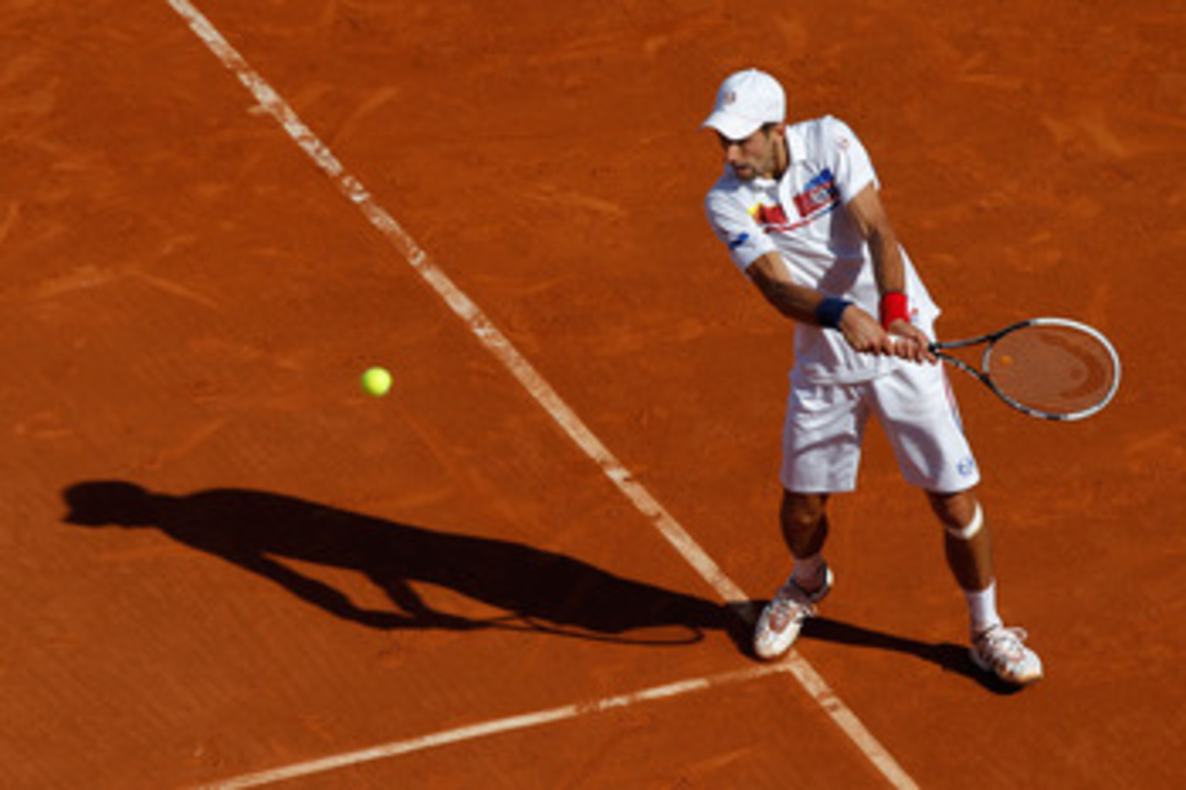 PARIS, FRANCE - MAY 29:  Novak Djokovic of Serbia hits a backhand during the men's singles round four match between Richard Gasquet of France and Novak Djokovic of Serbia on day eight of the French Open at Roland Garros on May 29, 2011 in Paris, France.
