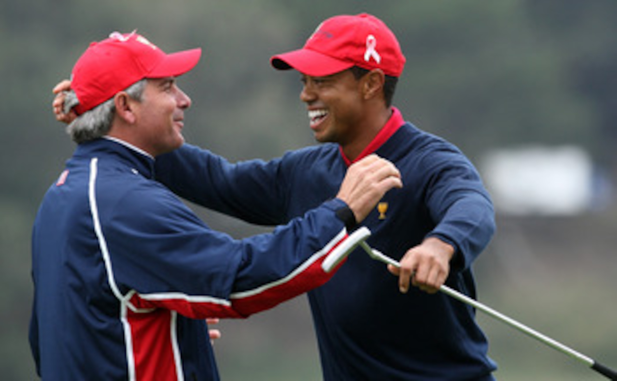 SAN FRANCISCO - OCTOBER 11:  Fred Couples the Captain of the USA Team races to congratulate Tiger Woods after he had holed the winning putt at the 13th hole where he beat his opponent Y.E.Yang 6&5 during the Day Four Singles Matches in The Presidents Cup