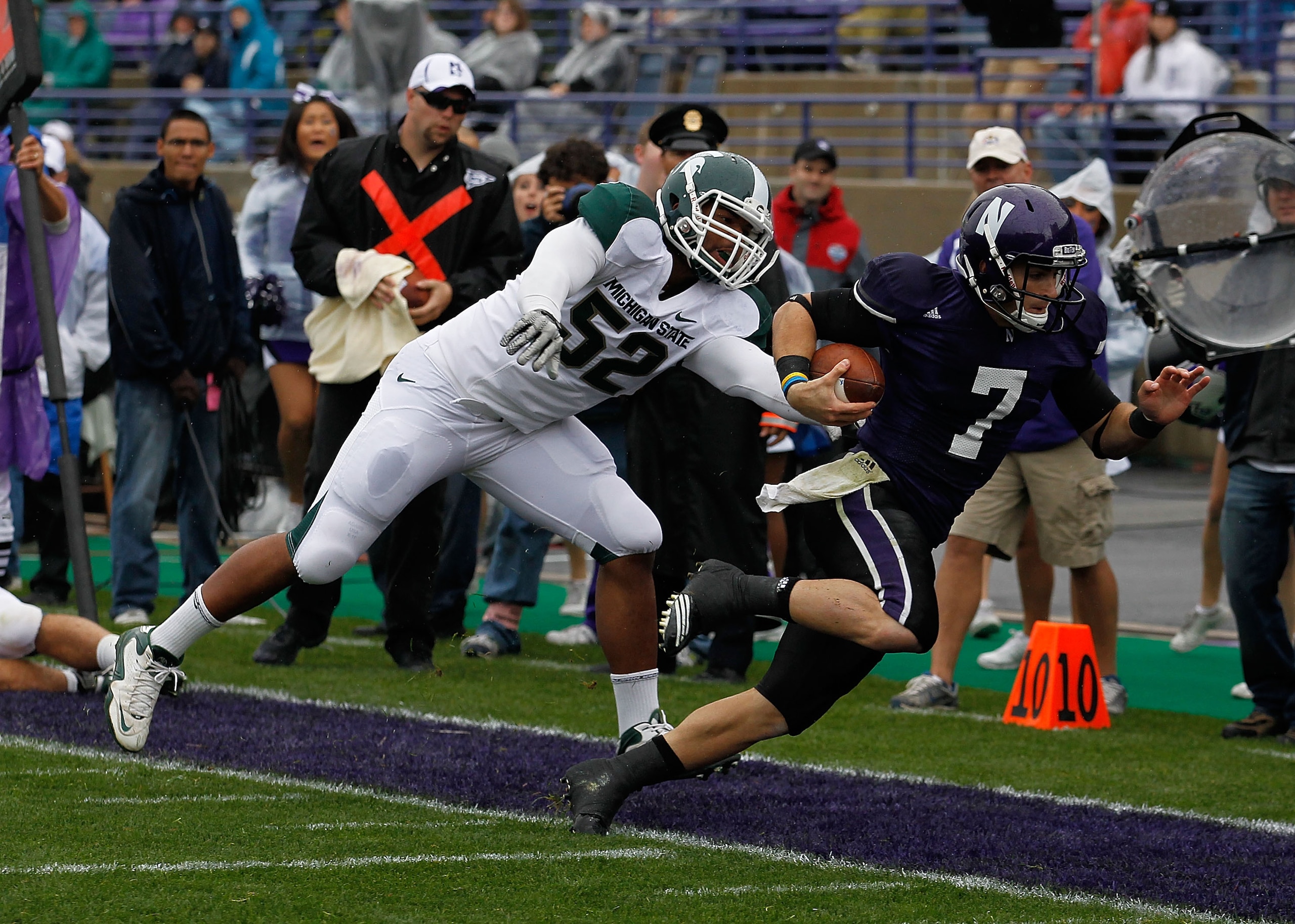 EVANSTON, IL - OCTOBER 23: Dan Persa #7 of the Northwestern Wildcats is knocked out of bounds short of the goalline by Denzel Drone #52 of the Michigan State Spartans at Ryan Field on October 23, 2010 in Evanston, Illinois. Michigan State defeated Northwe