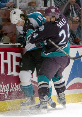 SAN DIEGO - DECEMBER 10:  Mike Ricci #19 of the San Jose Sharks is checked by Ruslan Salei #24 of the Anaheim Mighty Ducks during the 2nd period of their NHL game on December 10, 2003 at the Arrowhead Pond in Anaheim, California.  (Photo by Donald Miralle