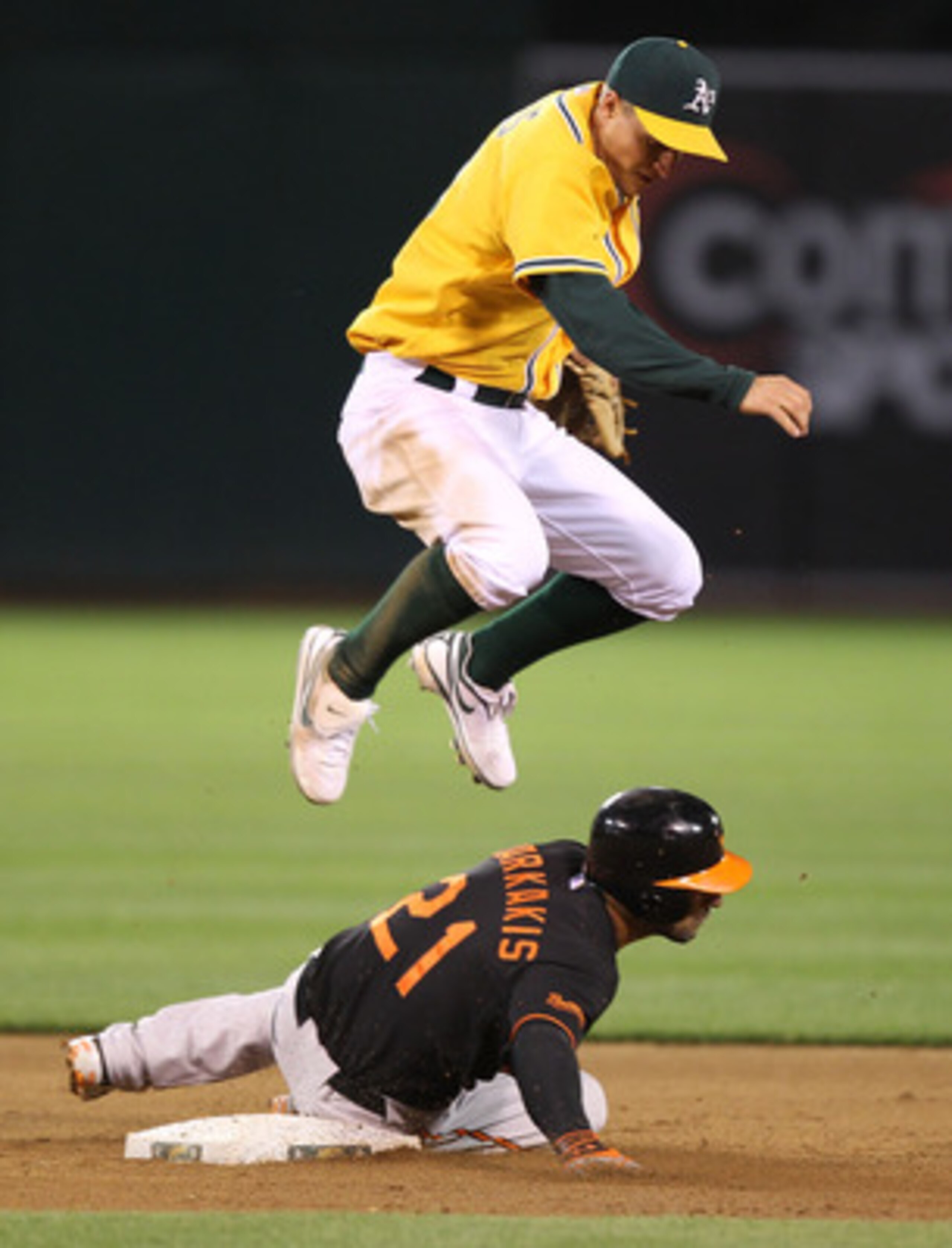 OAKLAND, CA - MAY 27:  Mark Ellis #14 of the Oakland Athletics jumps over Nick Markakis #21 of the Baltimore Orioles as he slides into second on a double play ball hit by Vladimir Guerrero in the fifth inning during a Major League Baseball game at the Oak