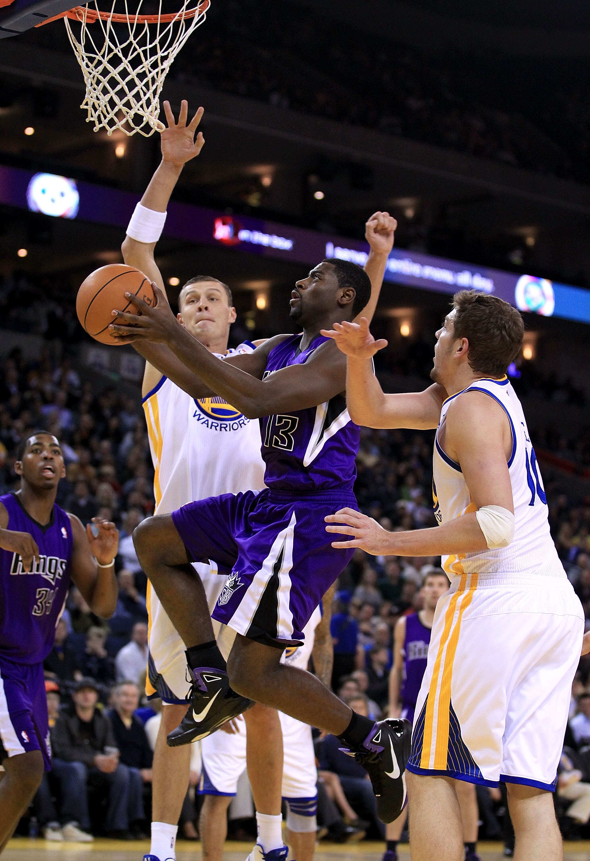 OAKLAND, CA - JANUARY 21:  Tyreke Evans #13 of the Sacramento Kings drives to the basket between Andris Biedrins #15 and David Lee #10 of the Golden State Warriors at Oracle Arena on January 21, 2011 in Oakland, California. NOTE TO USER: User expressly ac