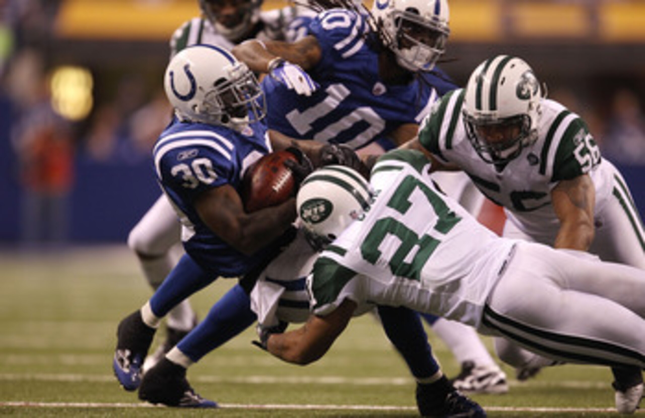 INDIANAPOLIS, IN - JANUARY 08:  Dominic Rhodes #30 of the Indianapolis Colts is tackled by Emanuel Cook #27 of the New York Jets during their 2011 AFC wild card playoff game at Lucas Oil Stadium on January 8, 2011 in Indianapolis, Indiana. The Jets won 17