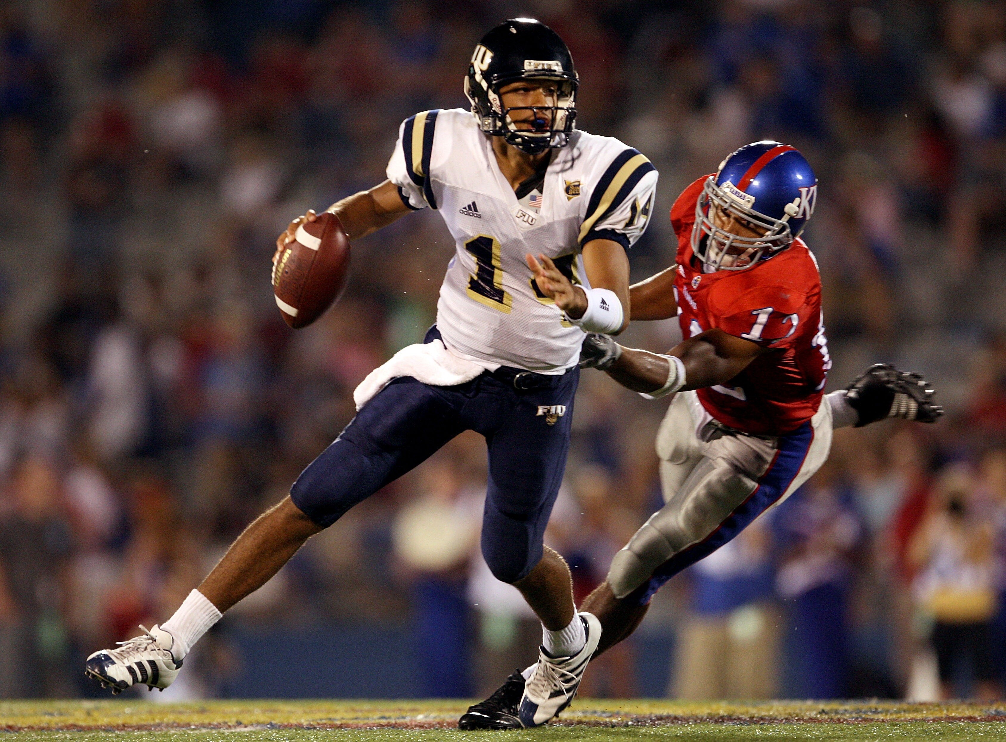 LAWRENCE, KS - SEPTEMBER 22:  Quarterback Wayne Younger #14 of the Florida International Golden Panthers is chased by James Holt #12 of the Kansas Jayhawks during the 2nd half of the game on September 22, 2007 at Memorial Stadium in Lawrence, Kansas.  (Ph