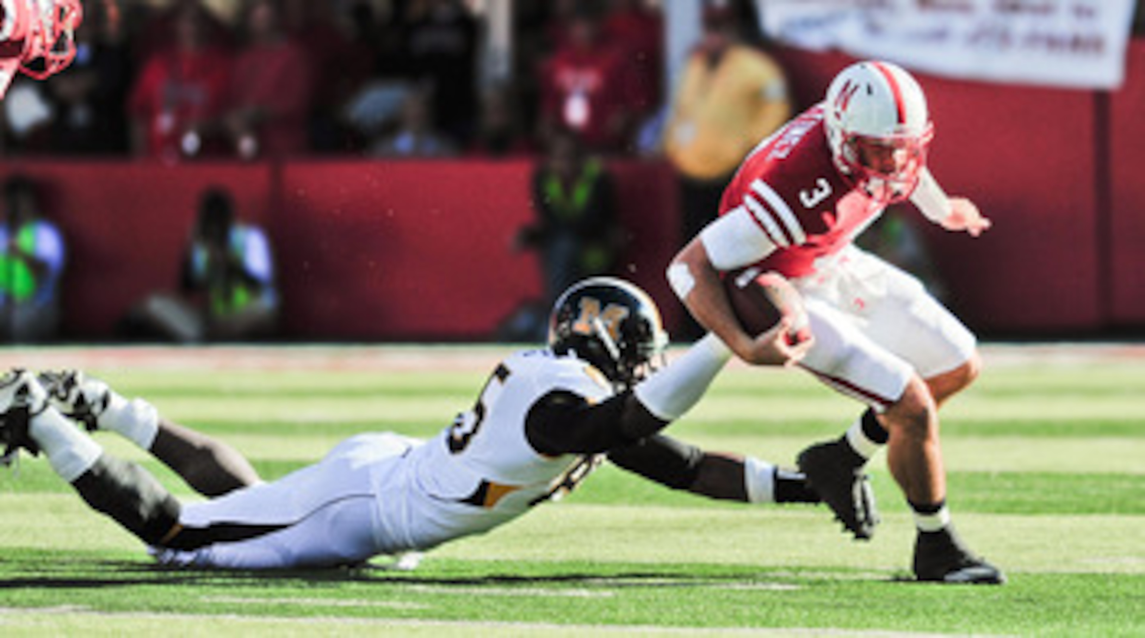 LINCOLN, NE - OCTOBER 30: Quarterback Taylor Martinez #3 of the Nebraska Cornhuskers tries to slip the grip of defensive end Aldon Smith #85 of the Missouri Tigers during first half action of their game at Memorial Stadium on October 30, 2010 in Lincoln,