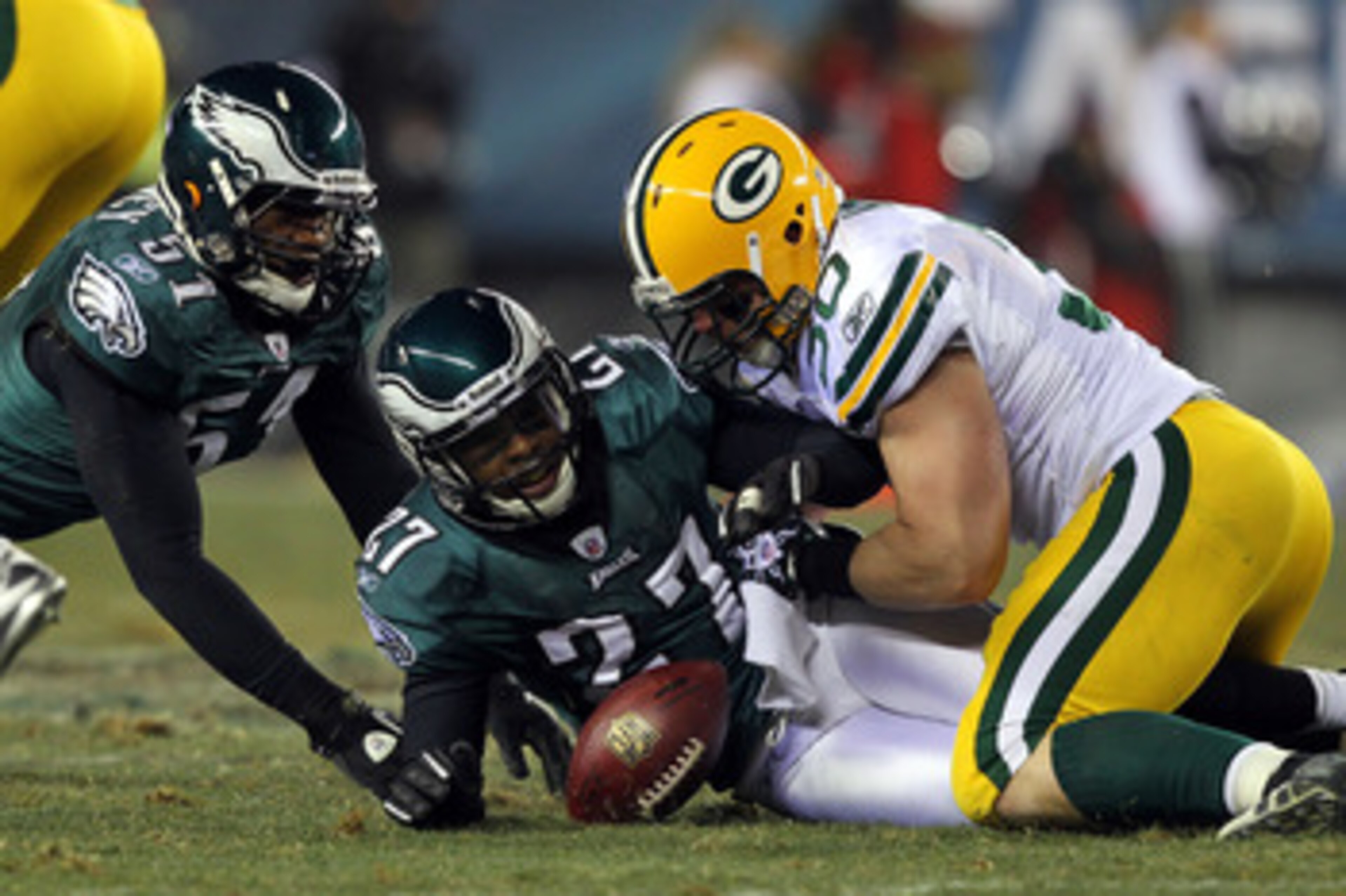 PHILADELPHIA, PA - JANUARY 09:  John Kuhn #30 of the Green Bay Packers fights for a fumble against Quintin Mikell #27 and Jamar Chaney #51 of the Philadelphia Eagles during the 2011 NFC wild card playoff game at Lincoln Financial Field on January 9, 2011 